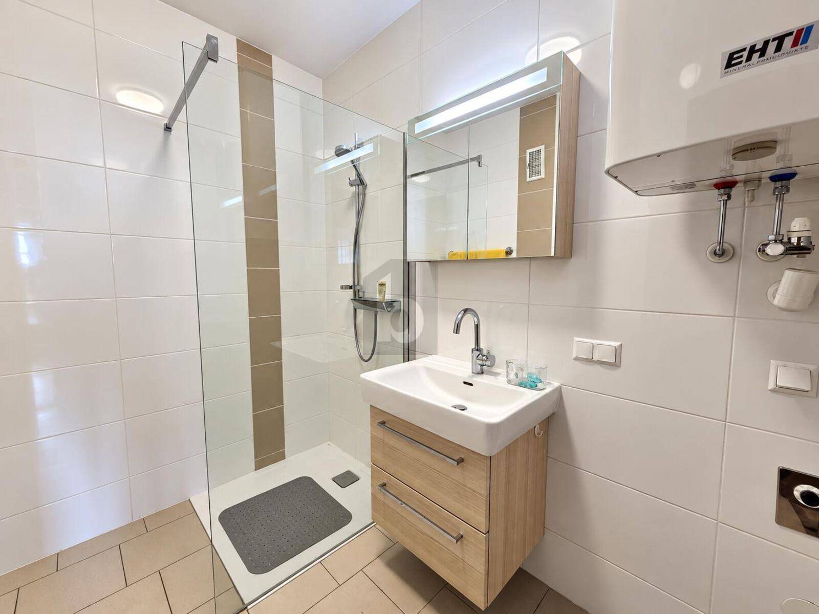 Modernes Badezimmer mit ebenerdiger Dusche, Waschbecken und Wandspiegel.