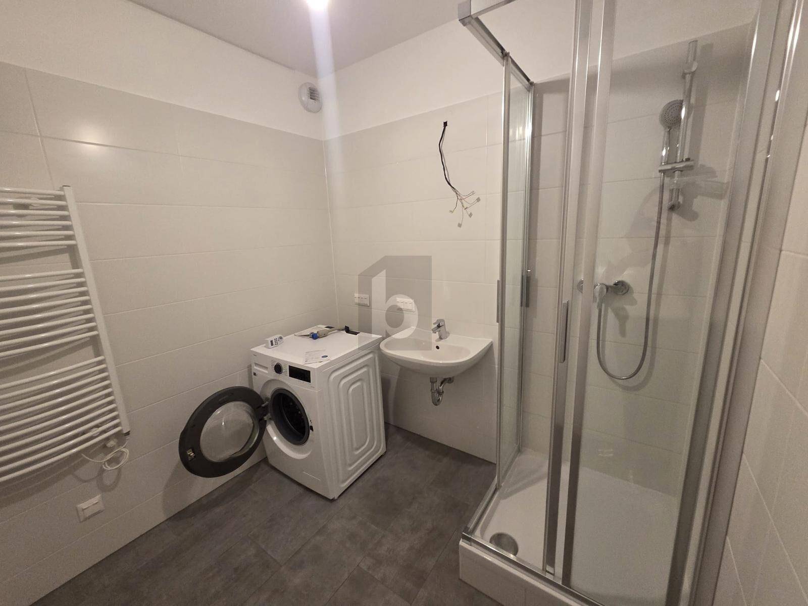 Modernes Badezimmer mit Duschkabine, Waschbecken, Waschmaschine und Handtuchheizkörper.