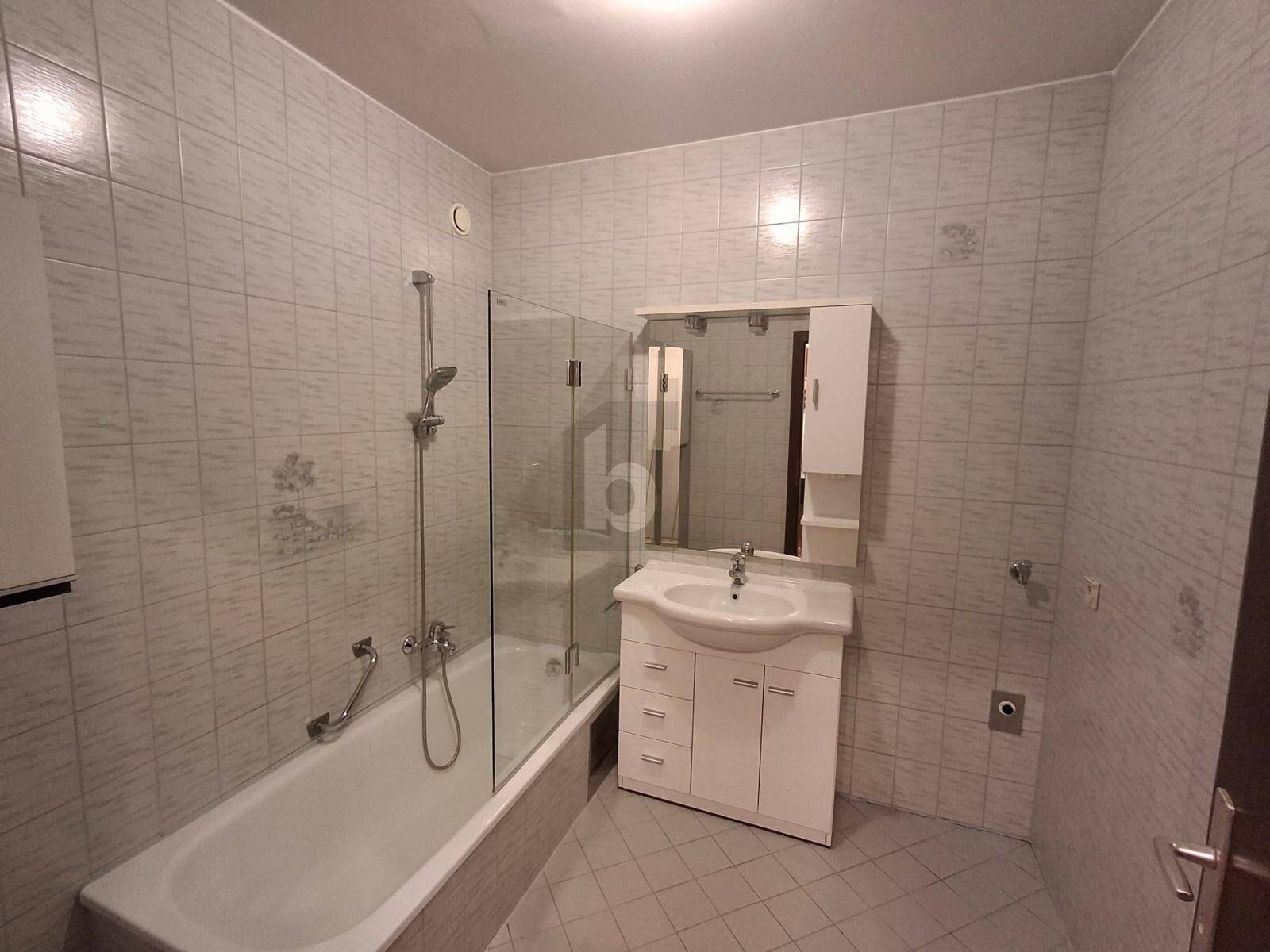 Funktionales Badezimmer mit Badewanne, Duschabtrennung, Waschbecken und Spiegelschrank.