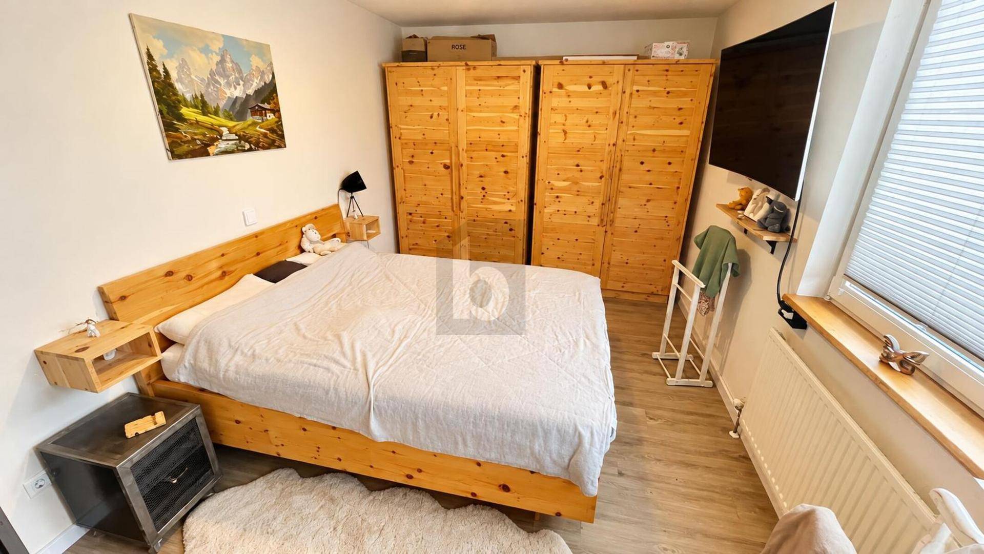 Gemütliches Schlafzimmer mit hellem Holzbett, passenden Kleiderschränken und einem Fenster für natürliches Licht.