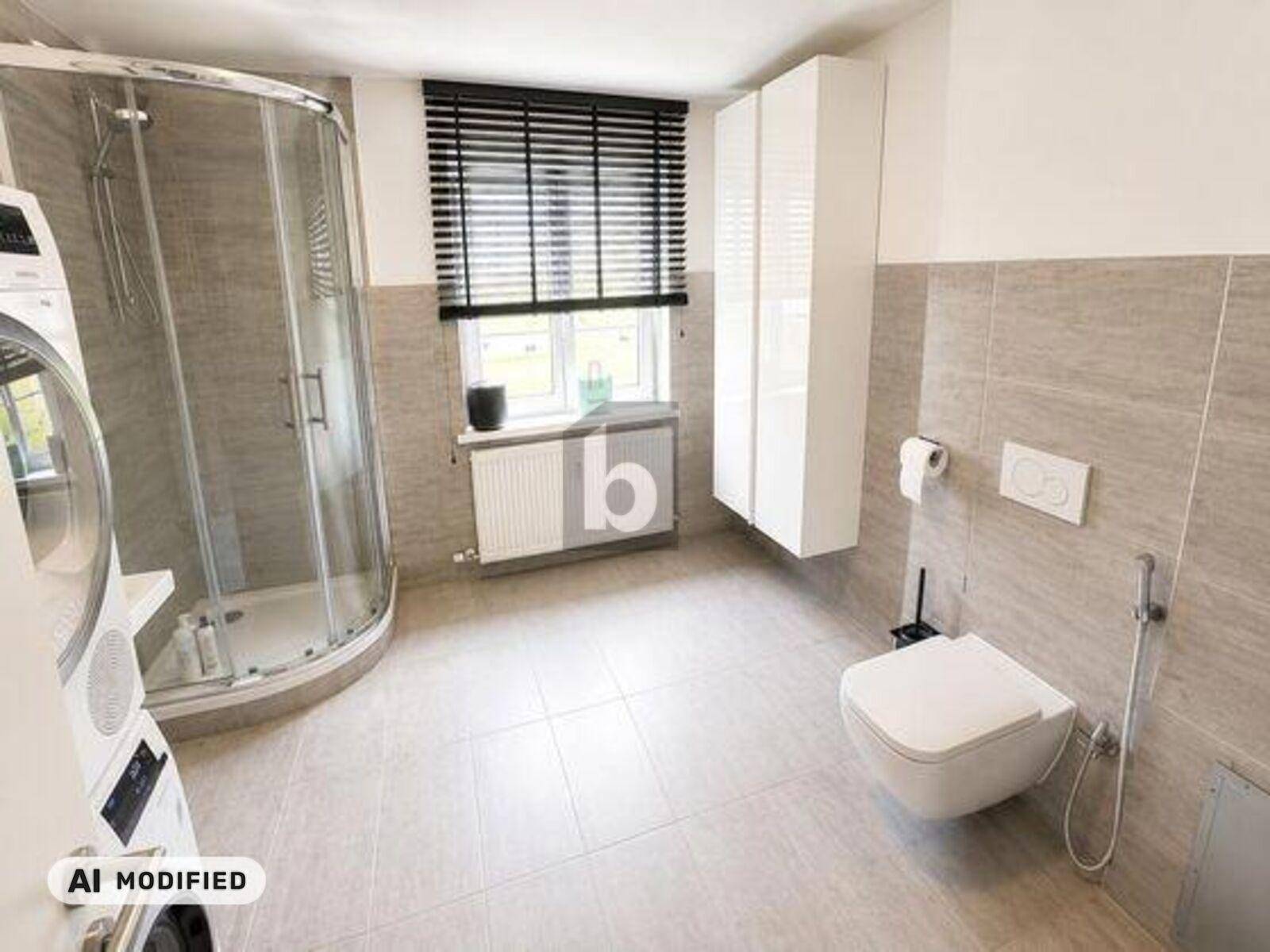 Modernes Badezimmer mit Duschkabine, Wand-WC, Waschmaschine und grauen Fliesen.
