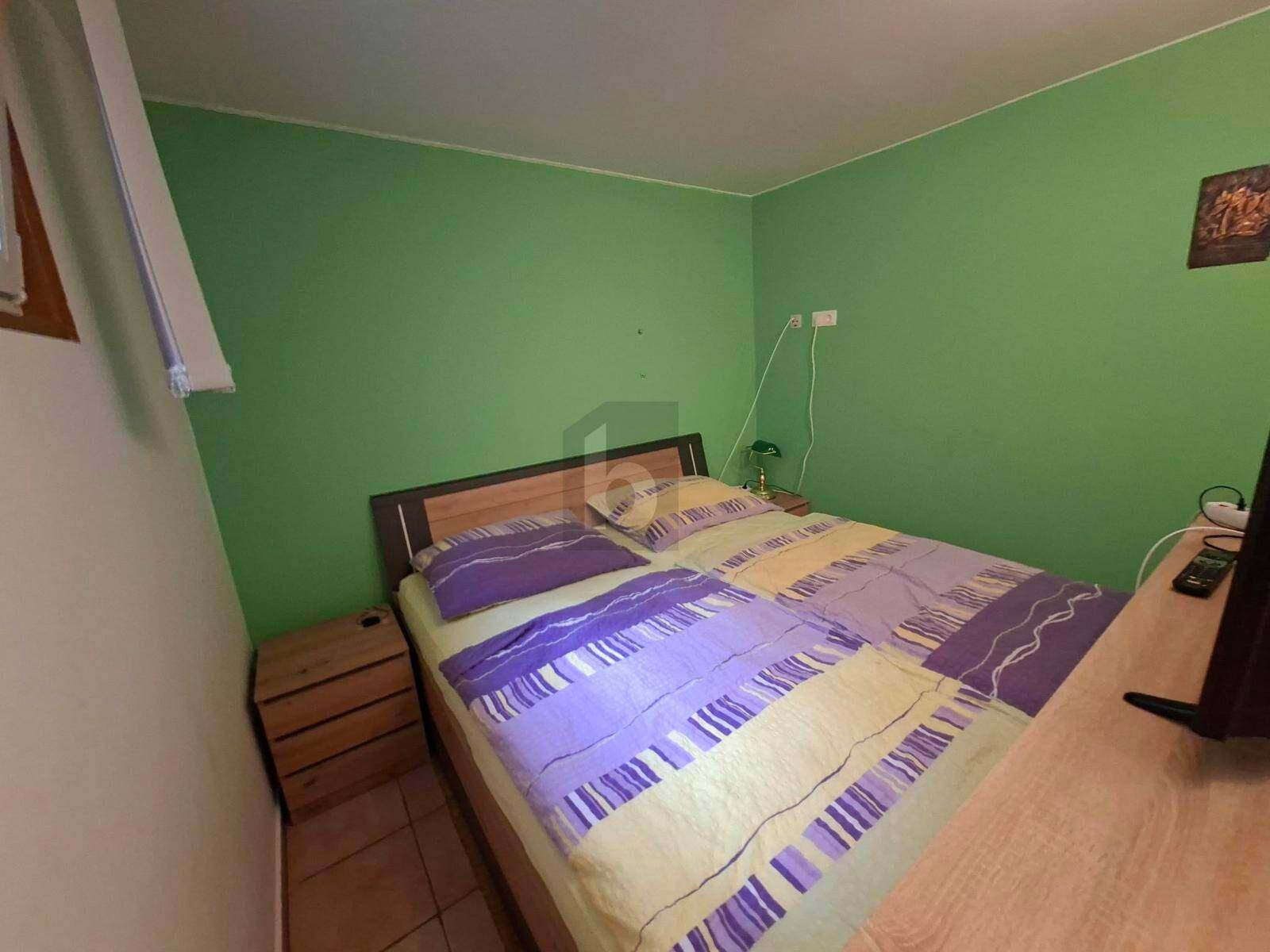 Gemütliches Schlafzimmer mit grünen Wänden, Doppelbett und Holzmöbeln.