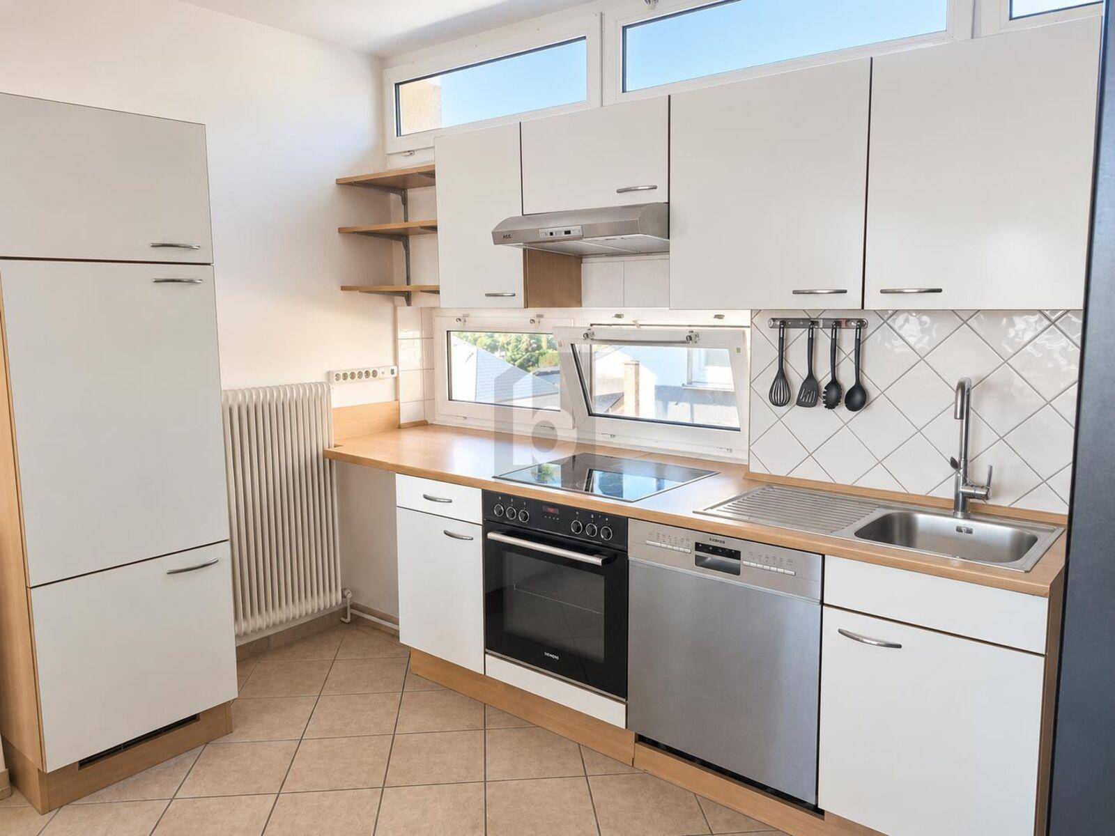 Funktionale Küche mit weißen Schränken, Holz-Arbeitsplatte und modernen Geräten.