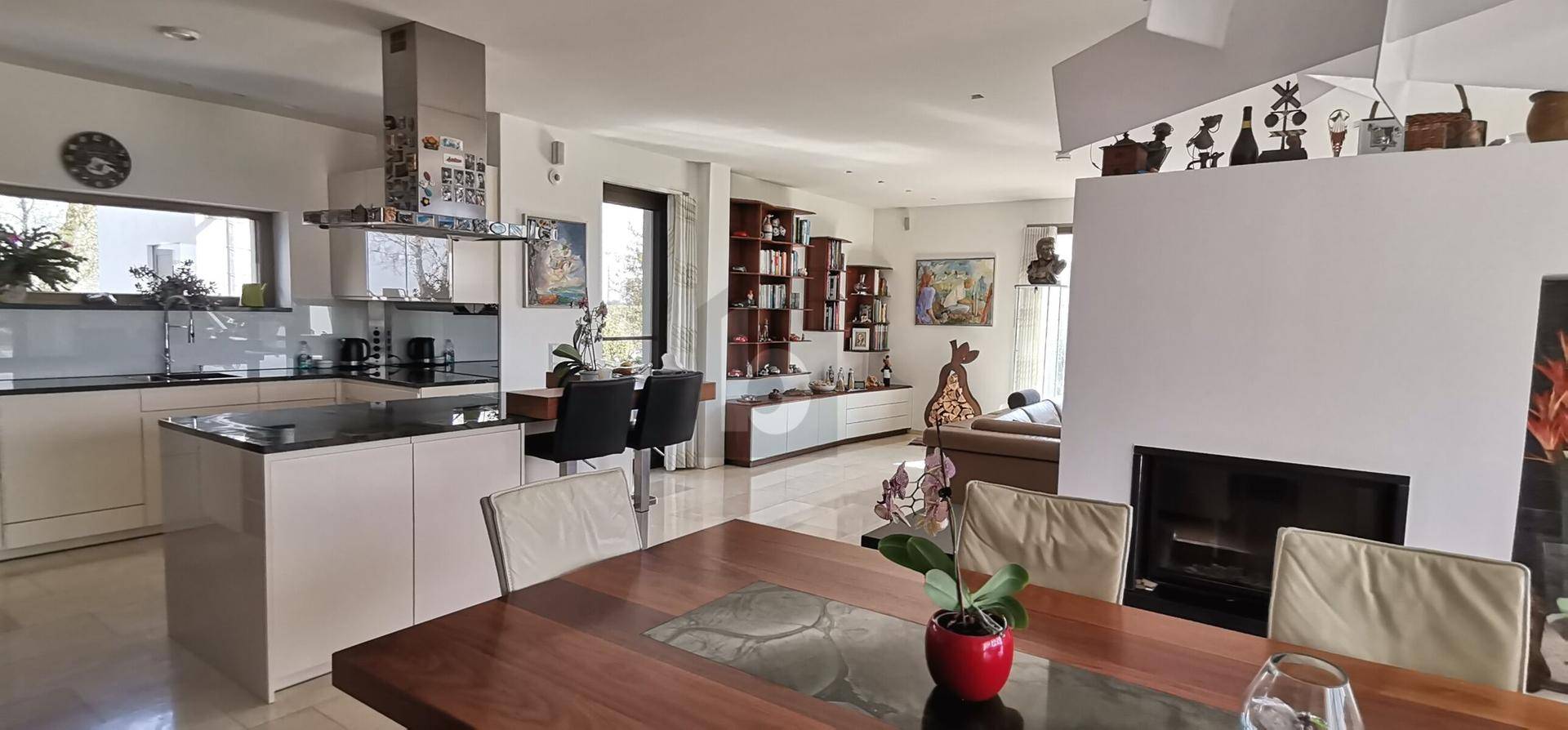 Moderne offene Küche mit Kochinsel und Essbereich, verbunden mit dem Wohnzimmer.