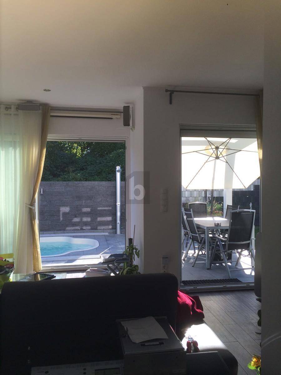Heller Wohnbereich mit Blick auf den Pool und die möblierte Terrasse durch große Glastüren.
