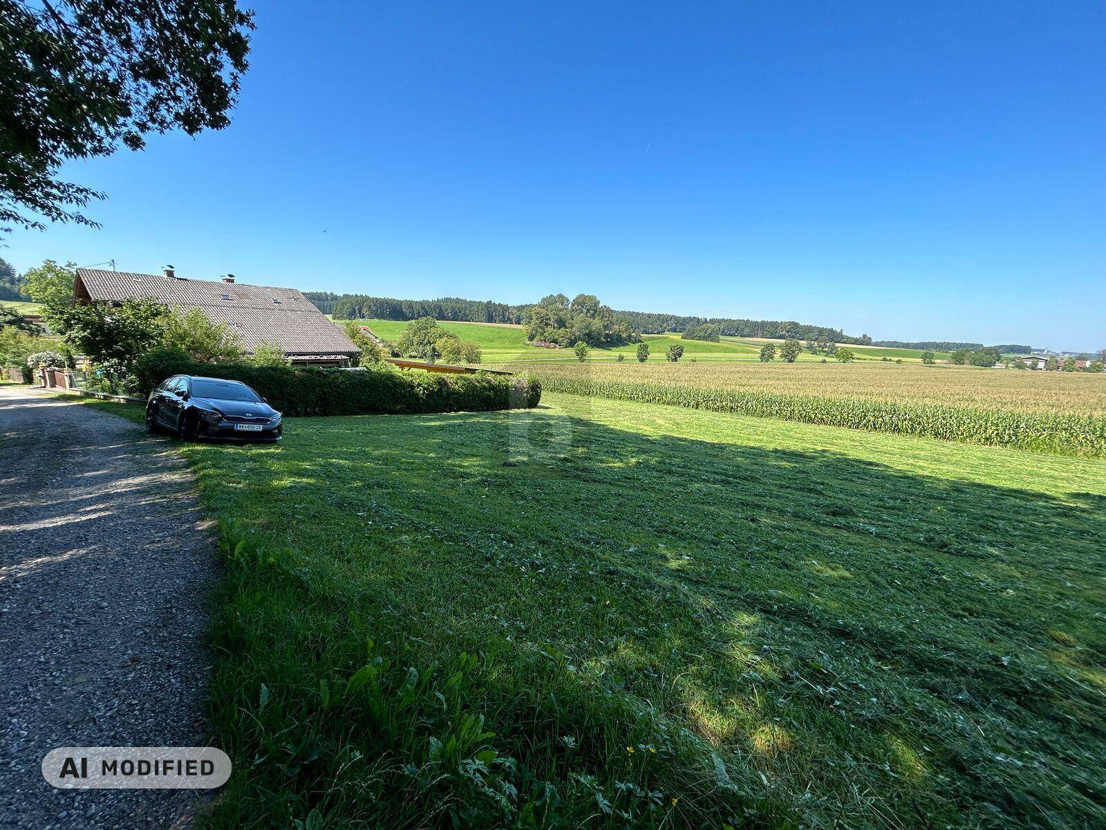 Idyllische ländliche Umgebung mit einem Haus, Auto und weiten Feldern unter klarem Himmel.