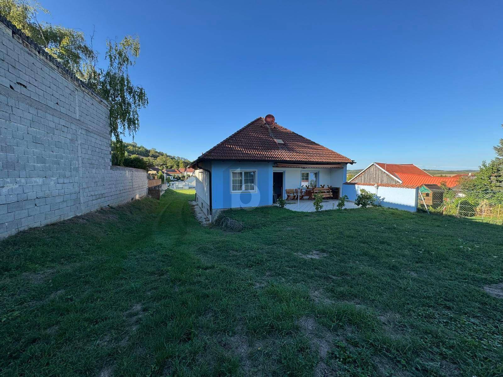 Rückseite des Hauses mit weitläufigem Rasen und Blick auf die umliegende Landschaft.