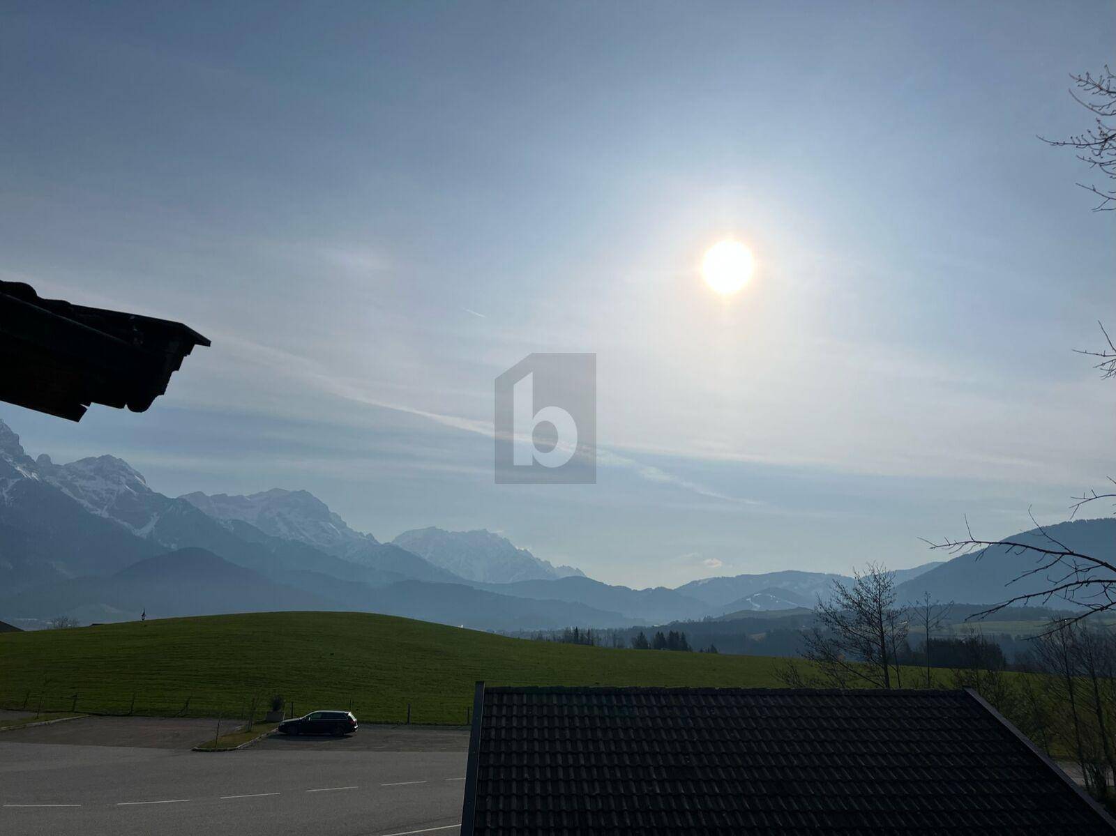 Panoramablick auf die majestätischen Berge und grüne Hügel unter einem strahlend blauen Himmel.