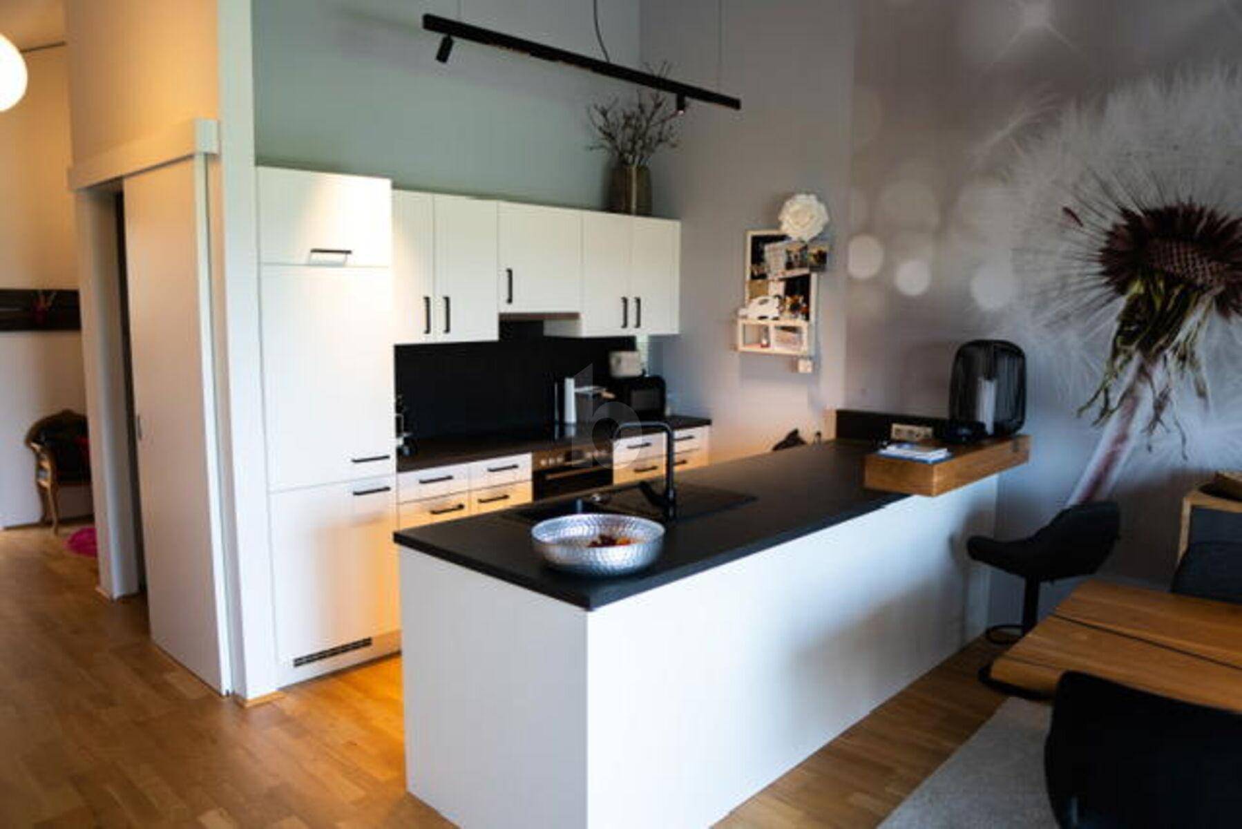 Moderne Küche mit weißen Schränken, dunklen Arbeitsplatten und einer Kücheninsel.