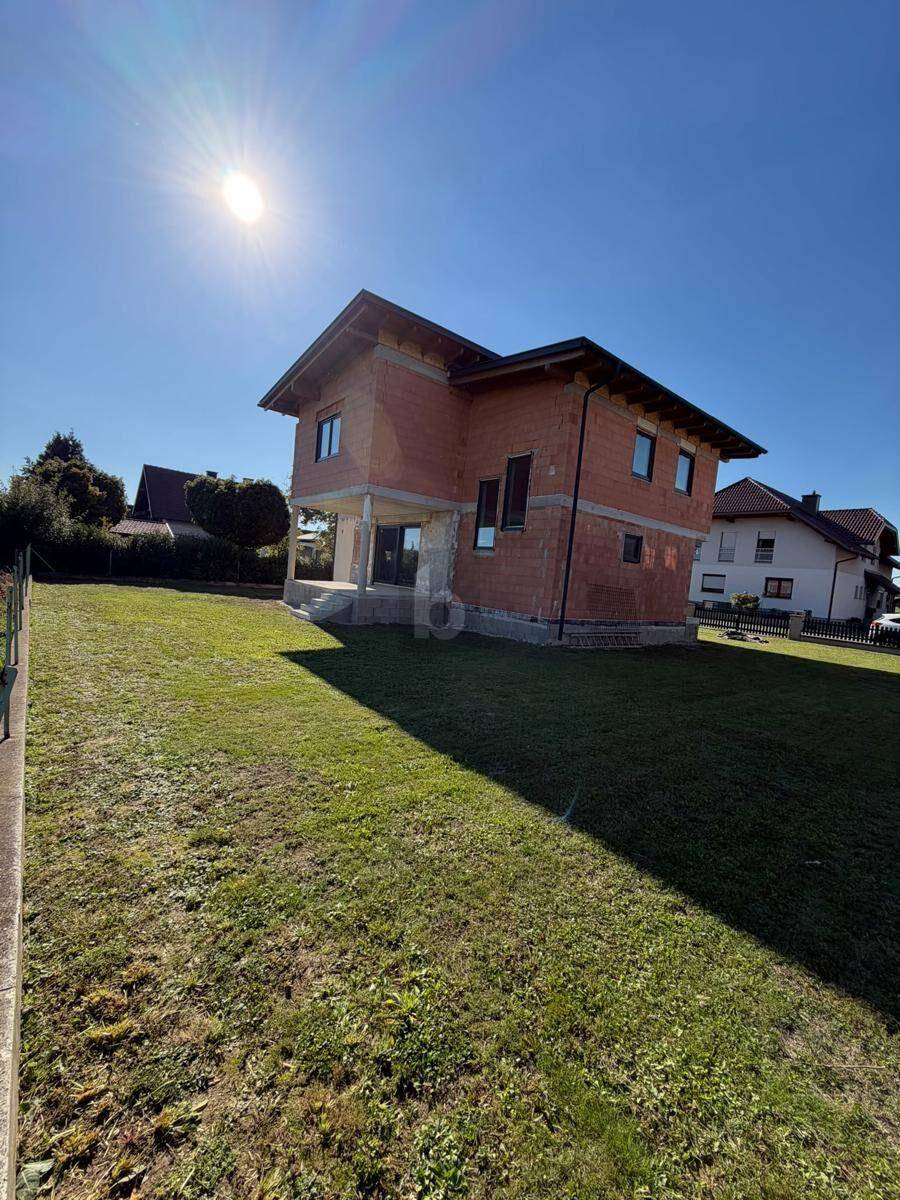 Einfamilienhaus im Rohbau mit großem Rasenbereich unter strahlendem Sonnenschein.
