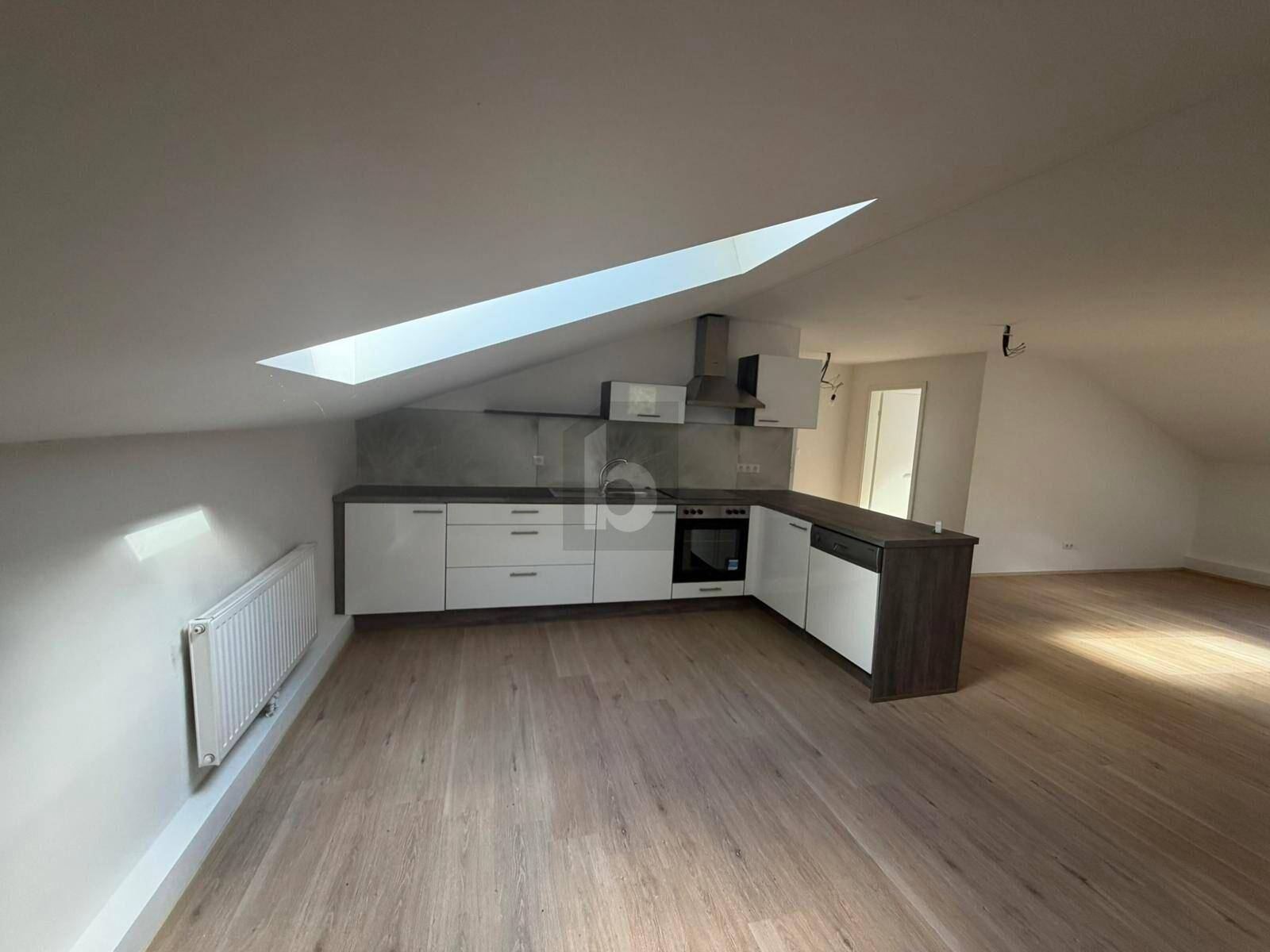 Moderne Küche im Dachgeschoss mit Schrägdach, Dachfenster und hellem Laminatboden.