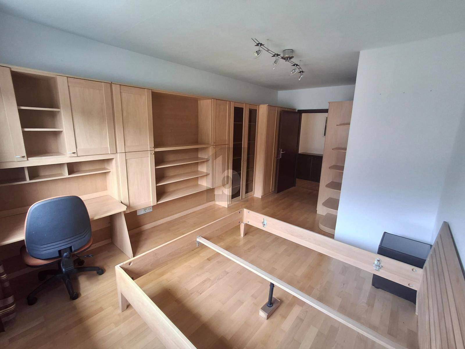 Schlafzimmer mit hellem Holzmobiliar, Bettrahmen und integrierten Regalen und Schreibtisch.