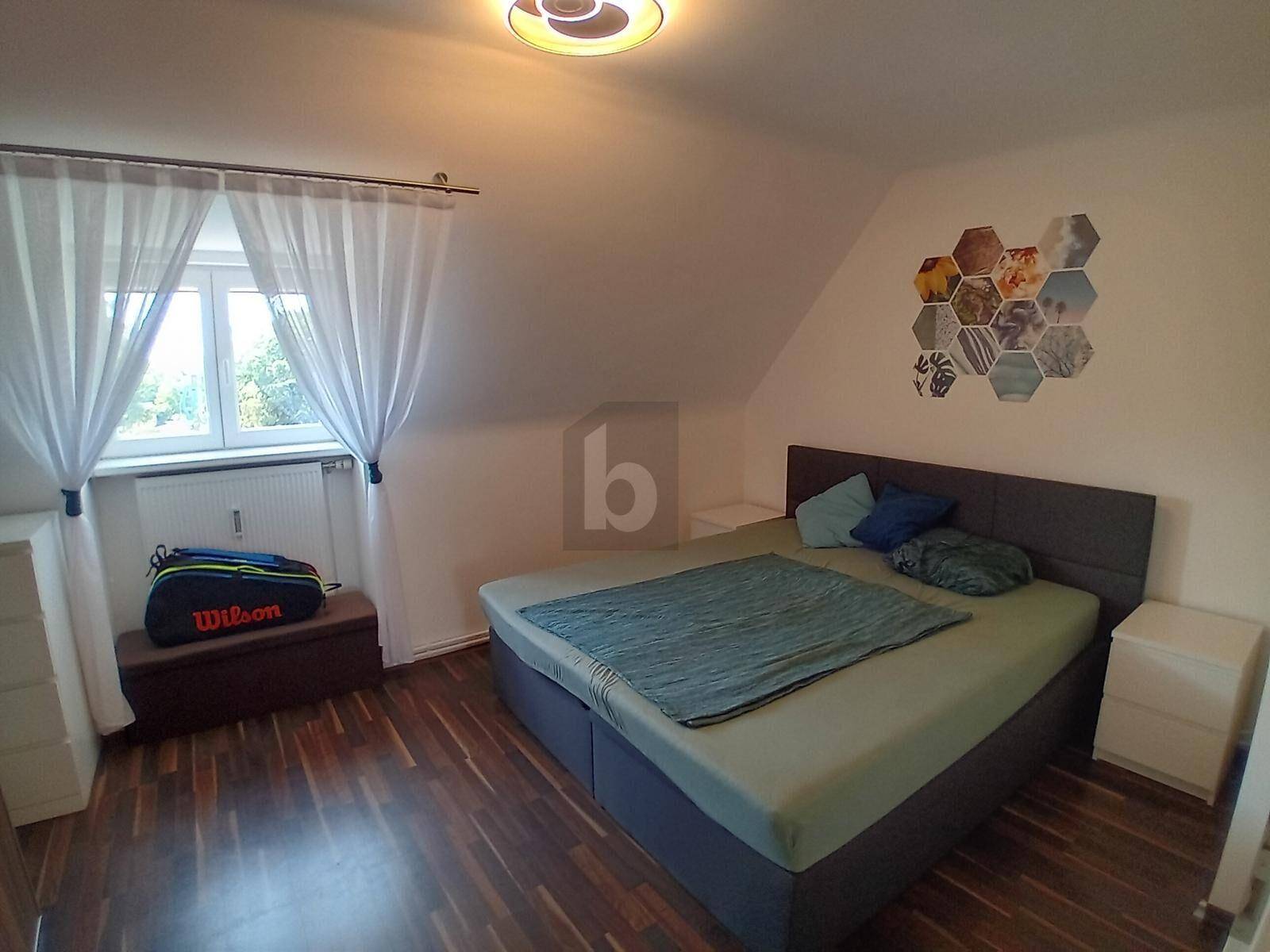 Helles Schlafzimmer mit Doppelbett, Dachschräge und Fenster mit Blick ins Grüne.