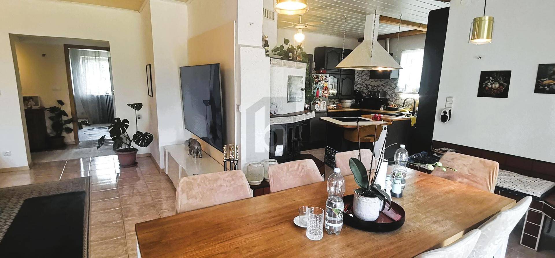 Heller Wohn-Essbereich mit Holztisch und Blick in die angrenzende Küche.