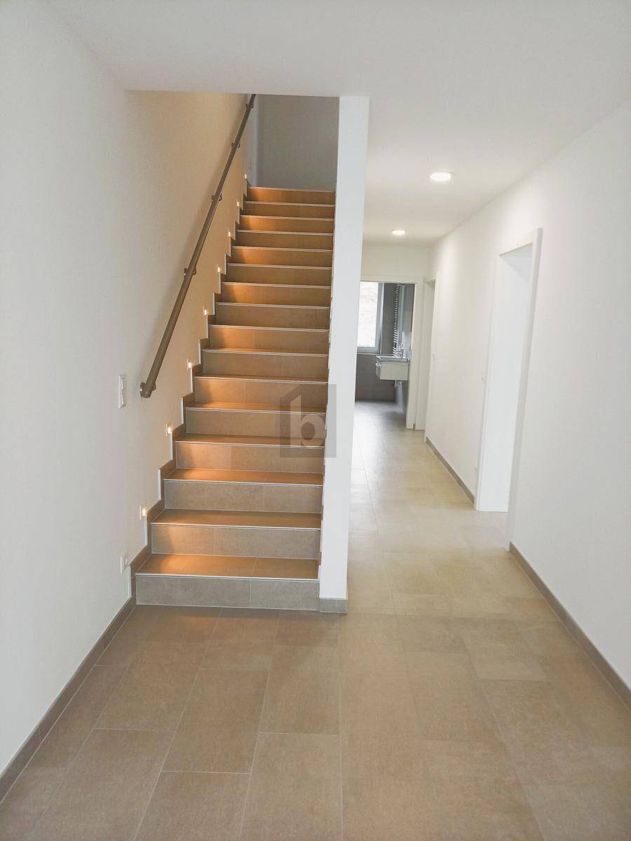 Heller Flur mit Treppe und Fliesenboden, der zu weiteren Räumen führt.