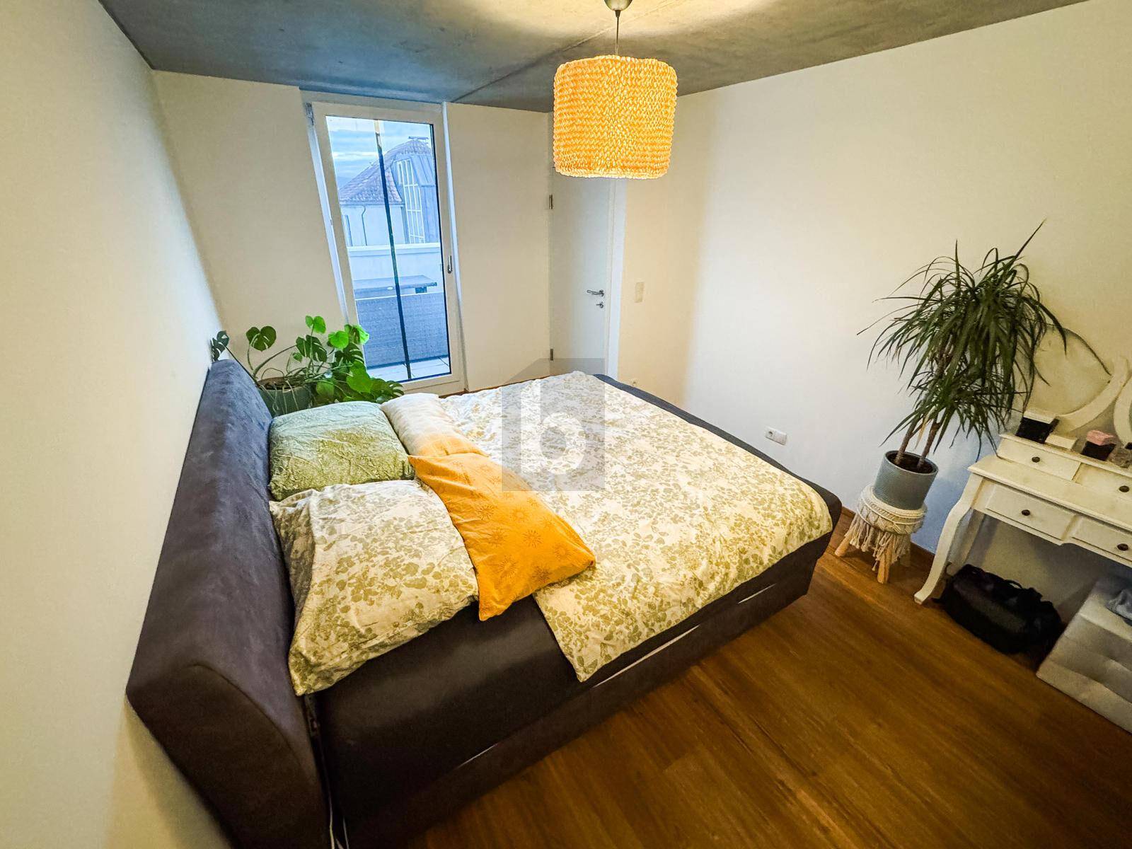 Schlafzimmer mit Holzboden, großem Bett und Zugang zu einem Balkon oder einer Terrasse.