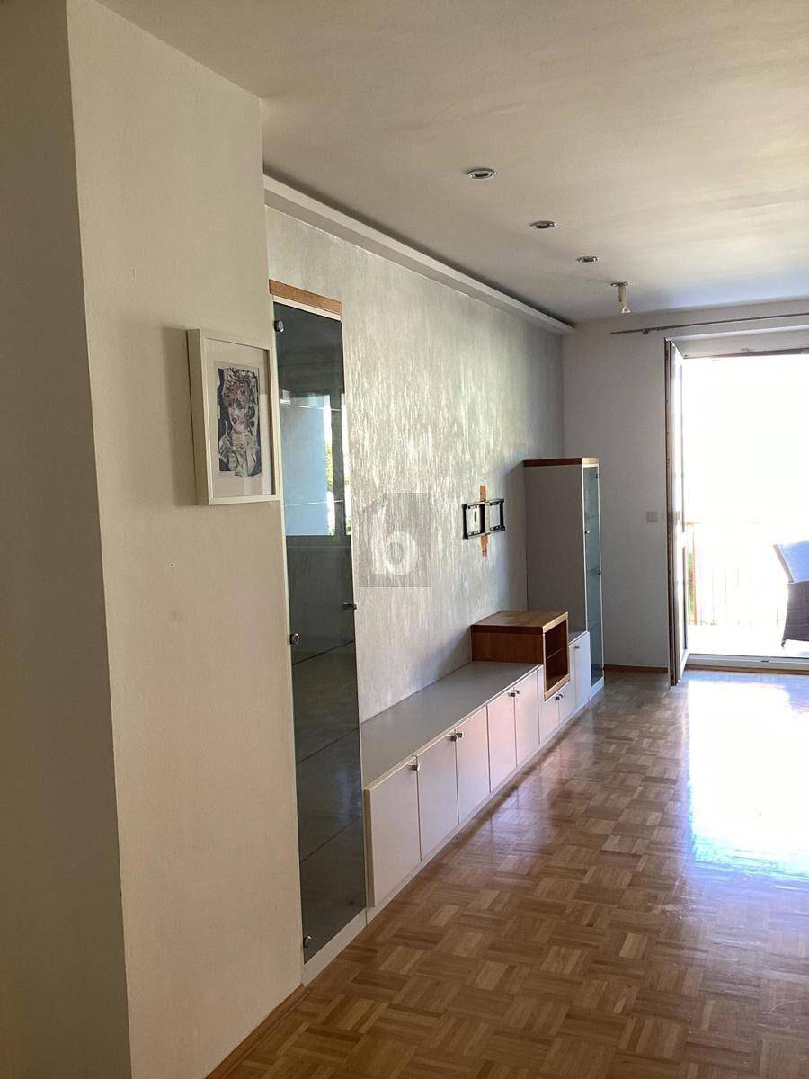 Helles Wohnzimmer mit Parkettboden und modernen Einbaumöbeln, das Zugang zu einem Außenbereich bietet.