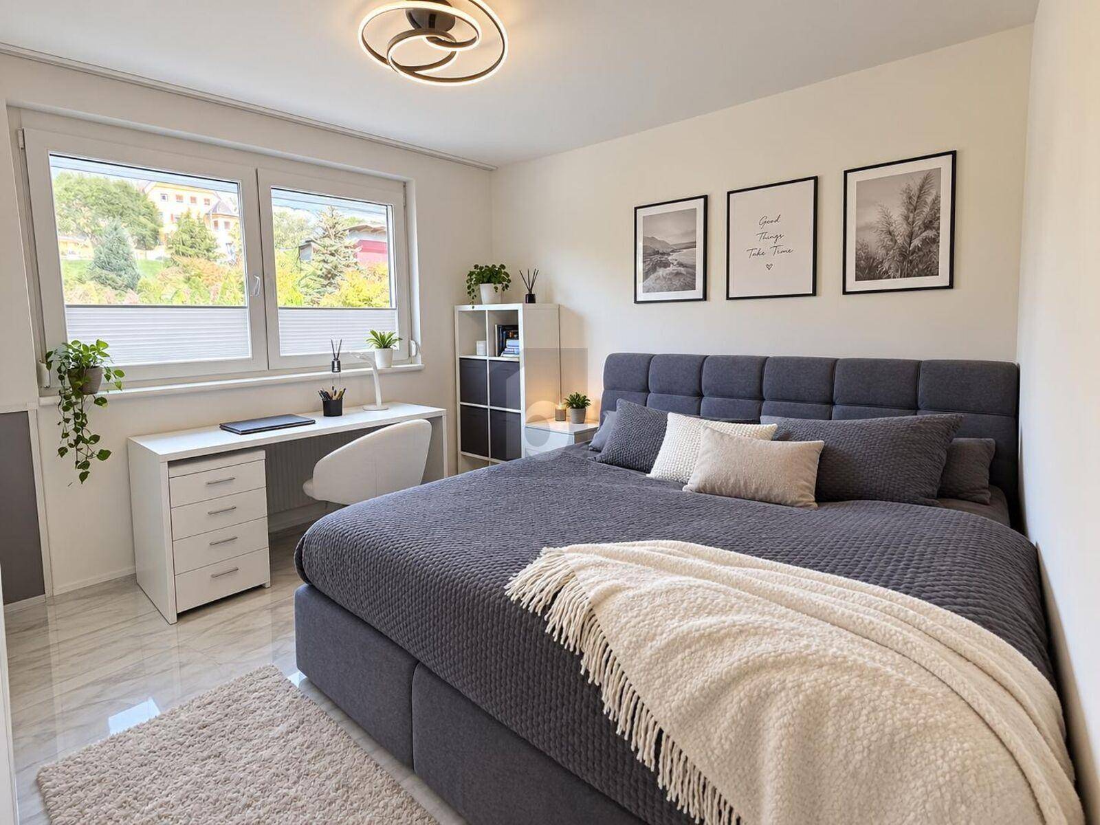 Modernes Schlafzimmer mit großem Doppelbett, Schreibtisch am Fenster und viel Tageslicht.
