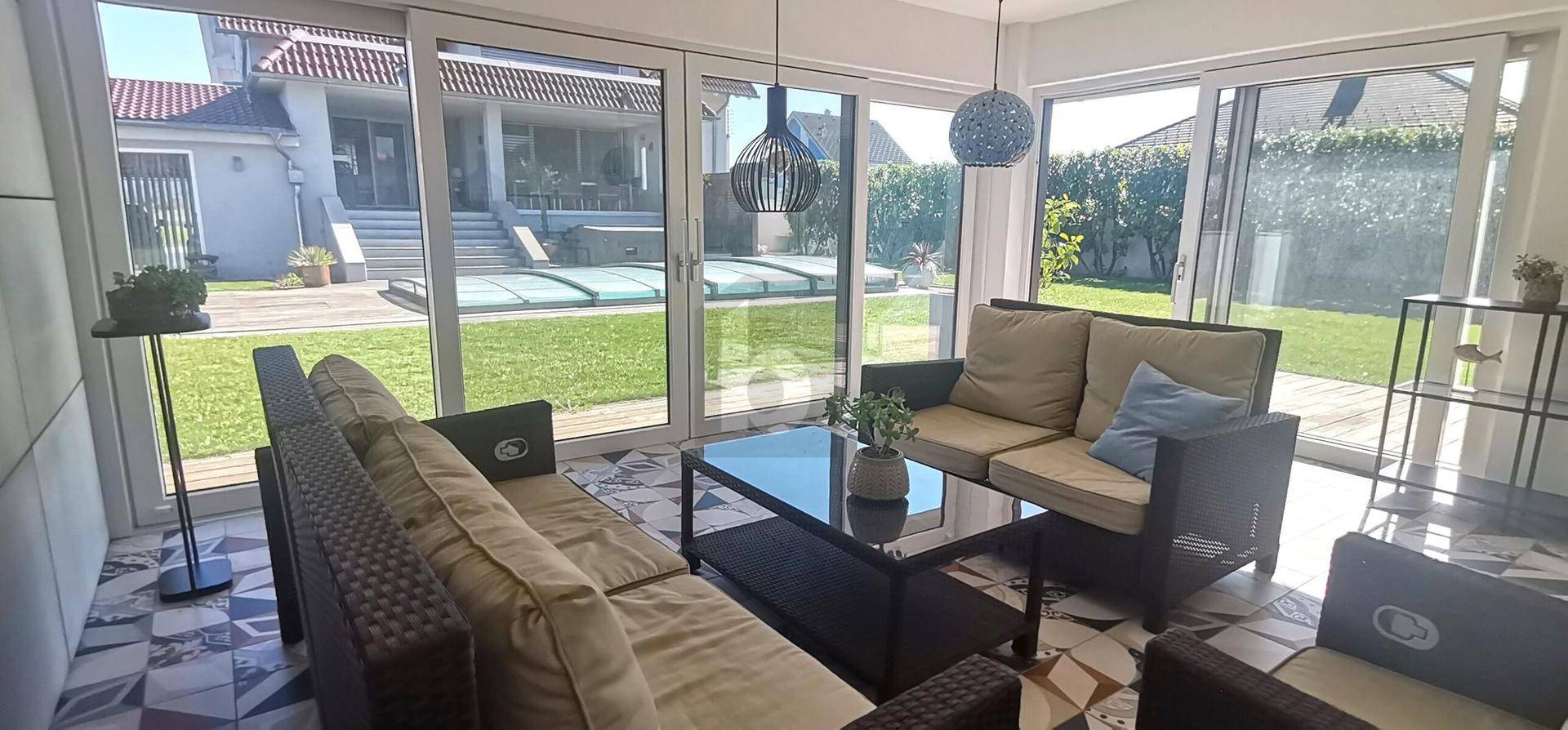 Lichtdurchflutetes Wohnzimmer mit bequemen Sofas und großen Glasfronten zum Garten.