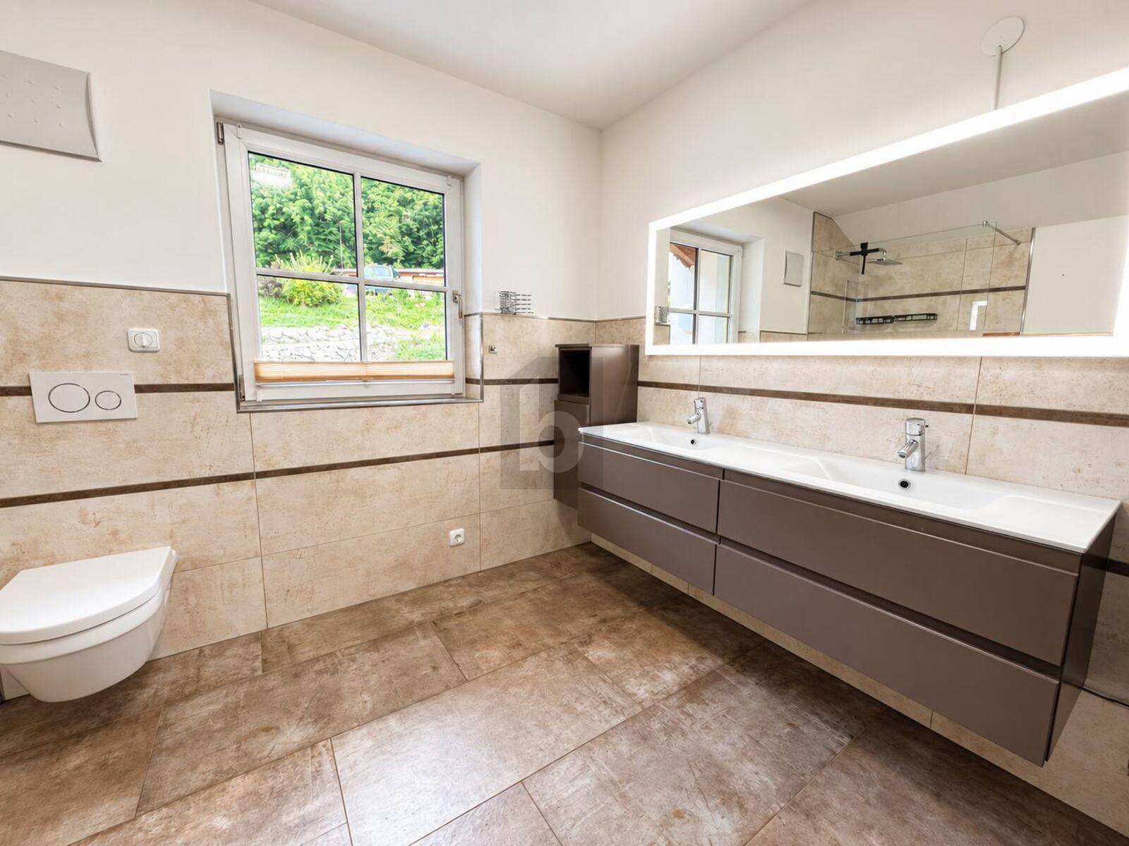 Modernes Badezimmer mit beigen Fliesen, Doppelwaschbecken, wandhängendem WC und Fenster.