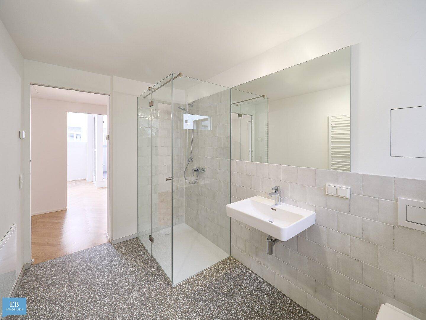 Modernes Badezimmer mit begehbarer Dusche, Einzelwaschbecken und großem Spiegel.