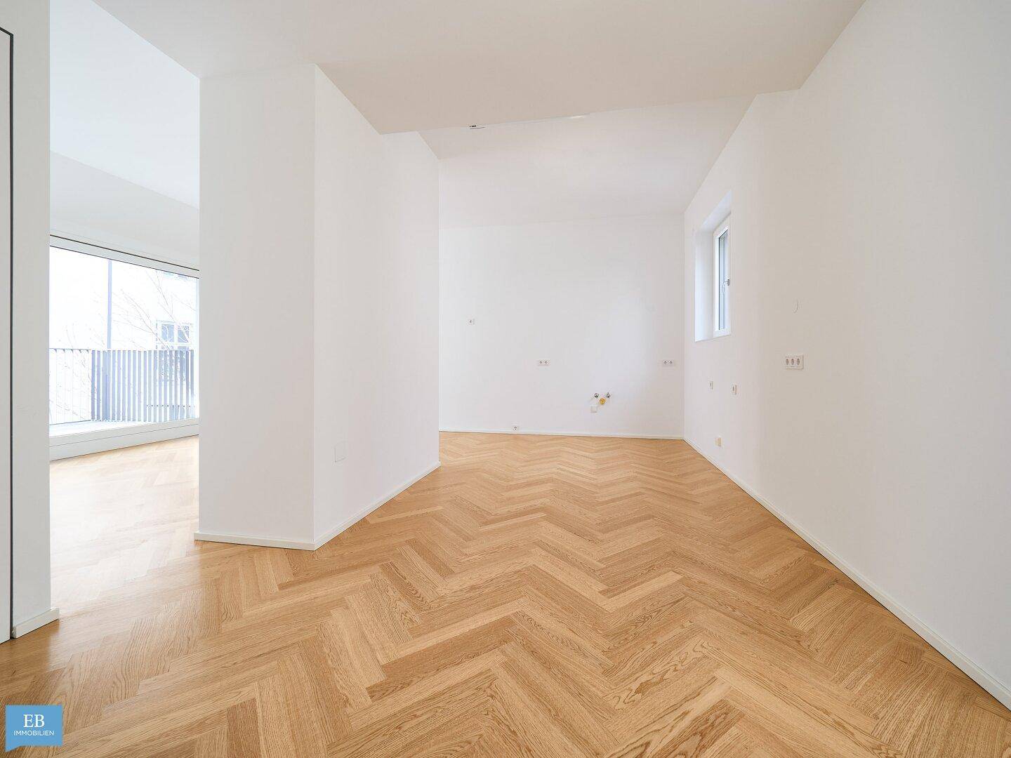 Offener Wohnbereich mit Fischgrätparkett und weiß gestrichenen Wänden, ideal für individuelle Gestaltung.