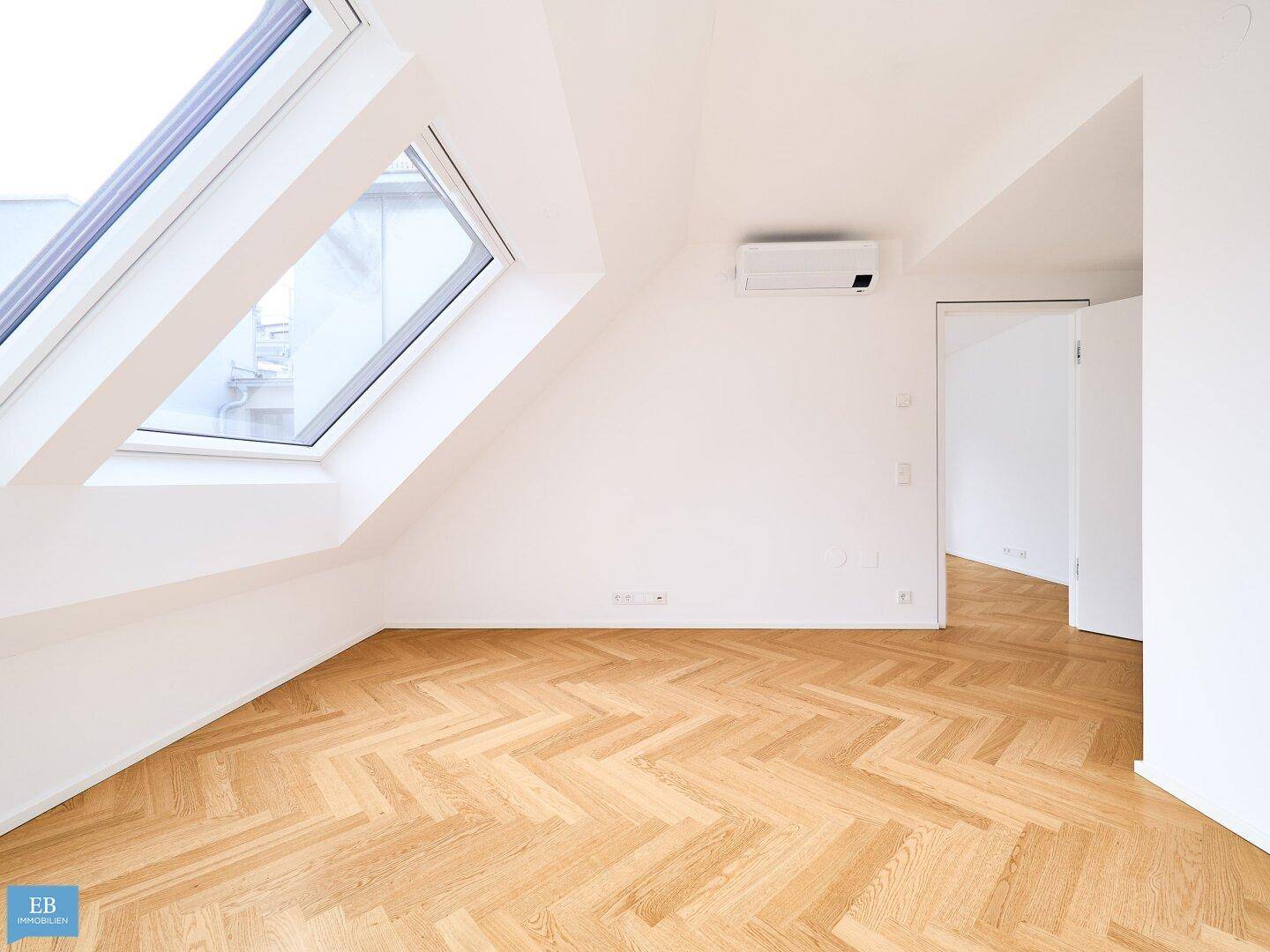 Helles Schlafzimmer mit Fischgrätparkett, Dachfenster und Klimaanlage, ideal für Komfort.