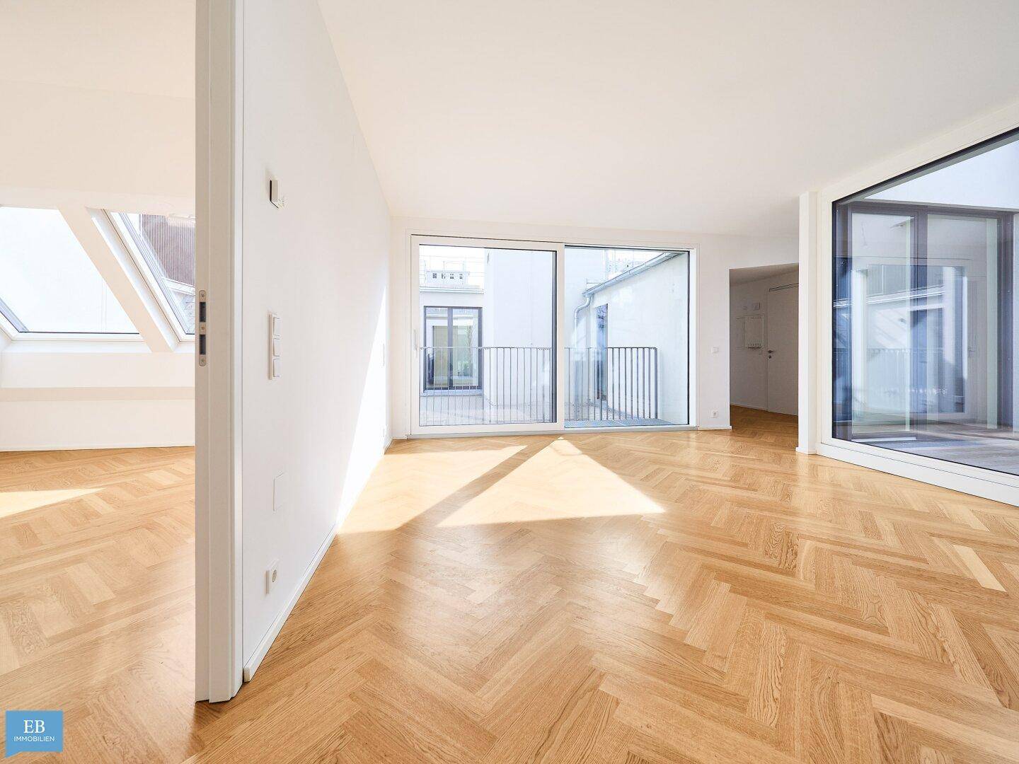 Lichtdurchfluteter Wohnraum mit Fischgrätparkett und großen Fensterfronten, die den Außenbereich integrieren.