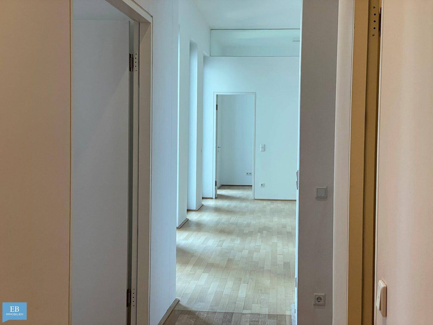 Heller Flur mit Parkettboden und Zugang zu weiteren Räumen, bietet eine offene Atmosphäre.