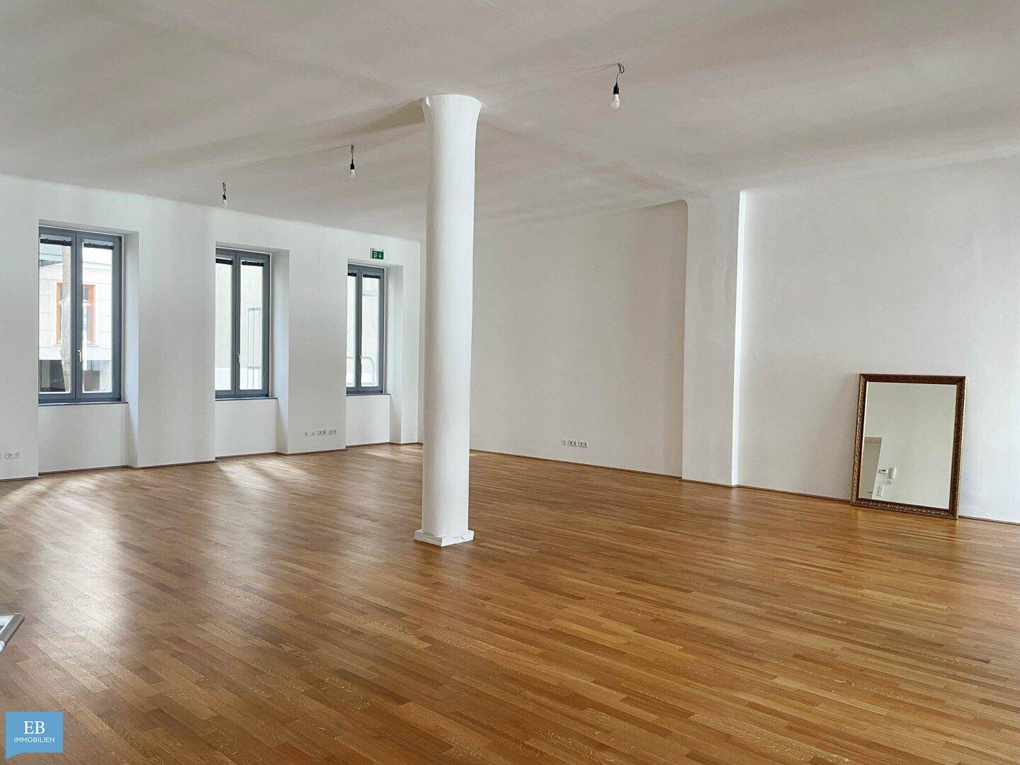 Heller Wohnraum mit Säule, Parkettboden und mehreren Fenstern, bietet viel Tageslicht.