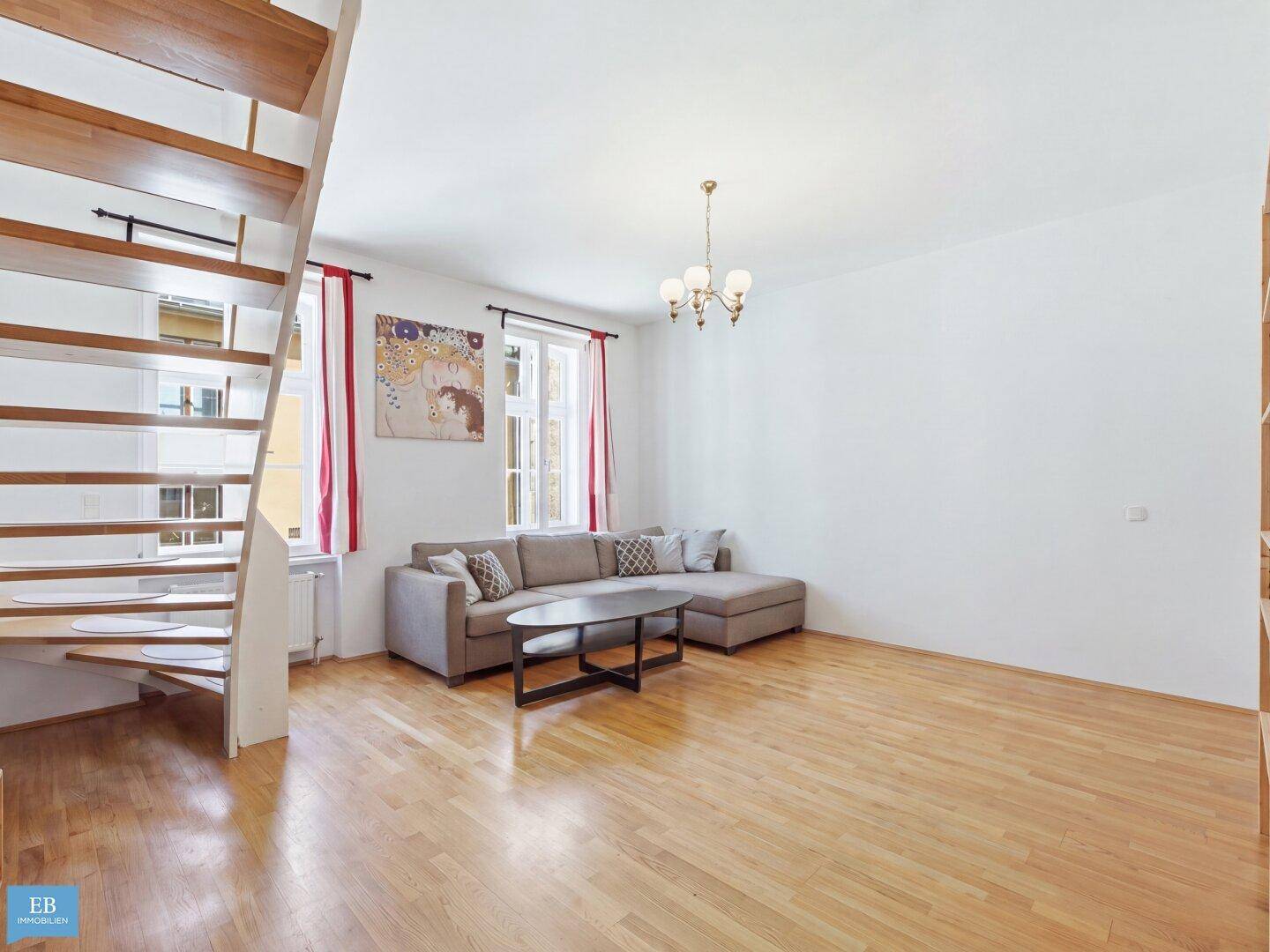 Gemütliches Wohnzimmer mit Sofa, Holzboden und offener Holztreppe.