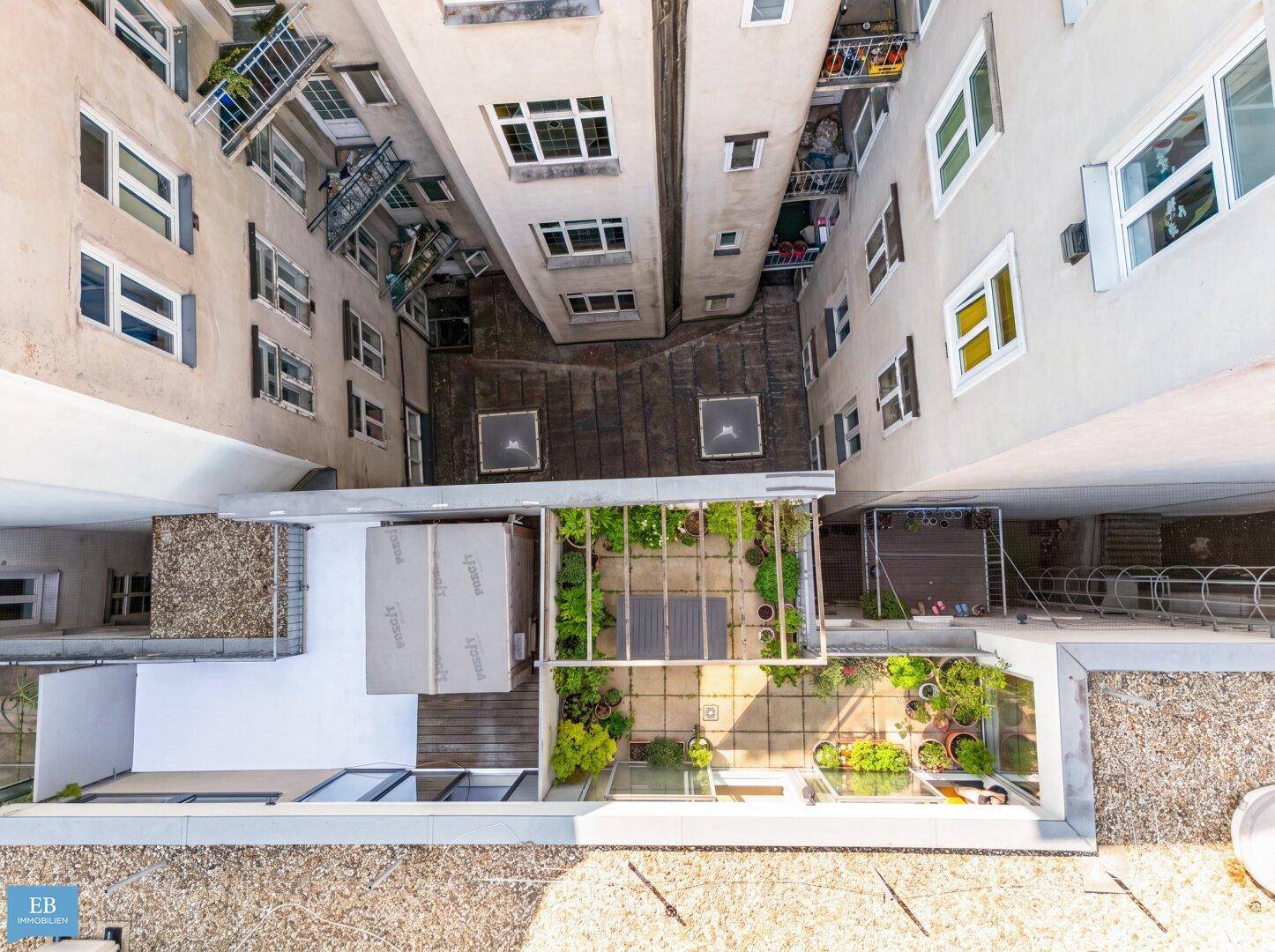 Vogelperspektive auf begrünte Terrassen und Innenhöfe eines Wohnkomplexes.