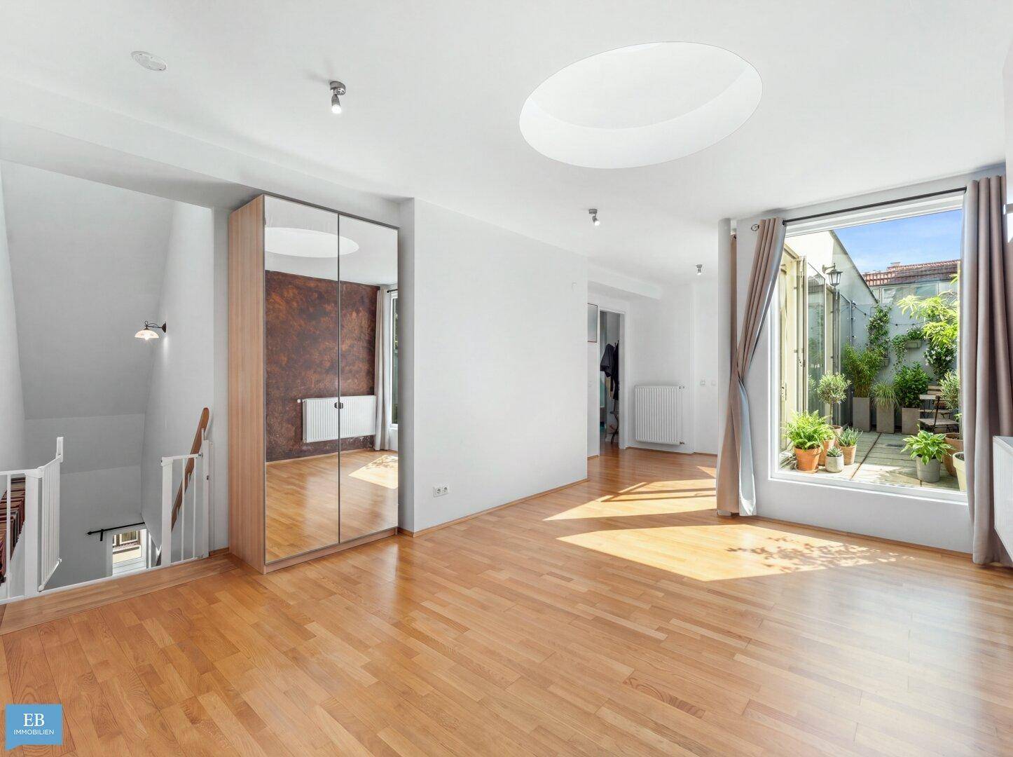Geräumiger Wohnbereich mit Oberlicht, Spiegelschrank und Treppenaufgang.