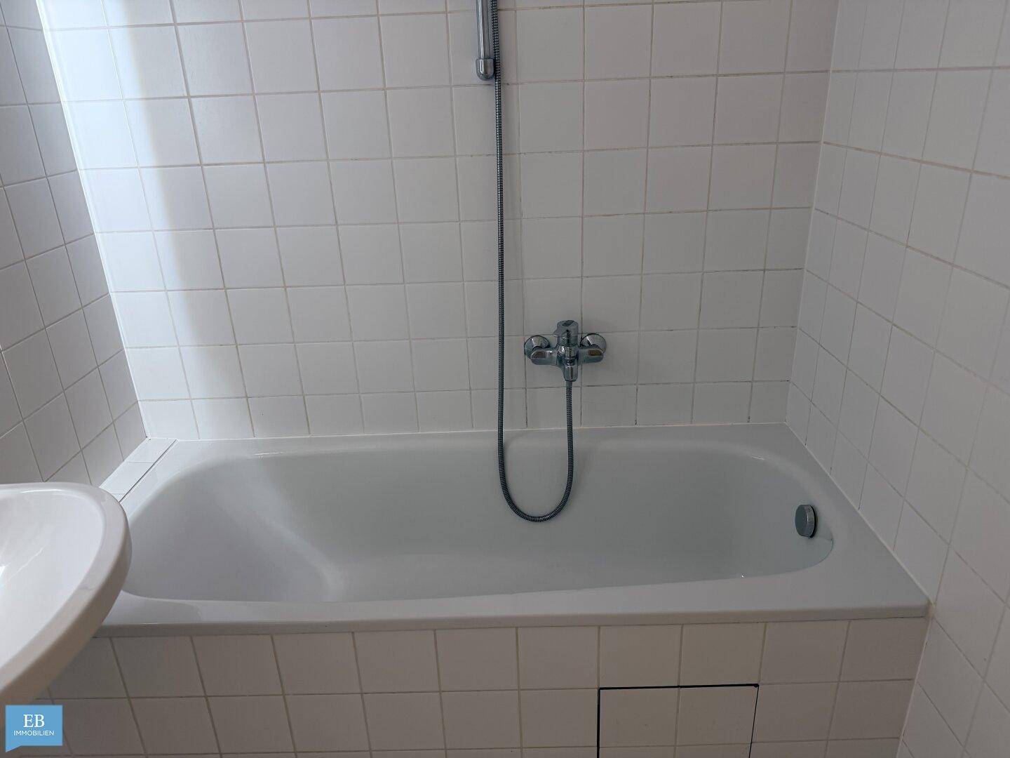 Nahaufnahme der Badewanne und der weißen Wandfliesen im Badezimmer.