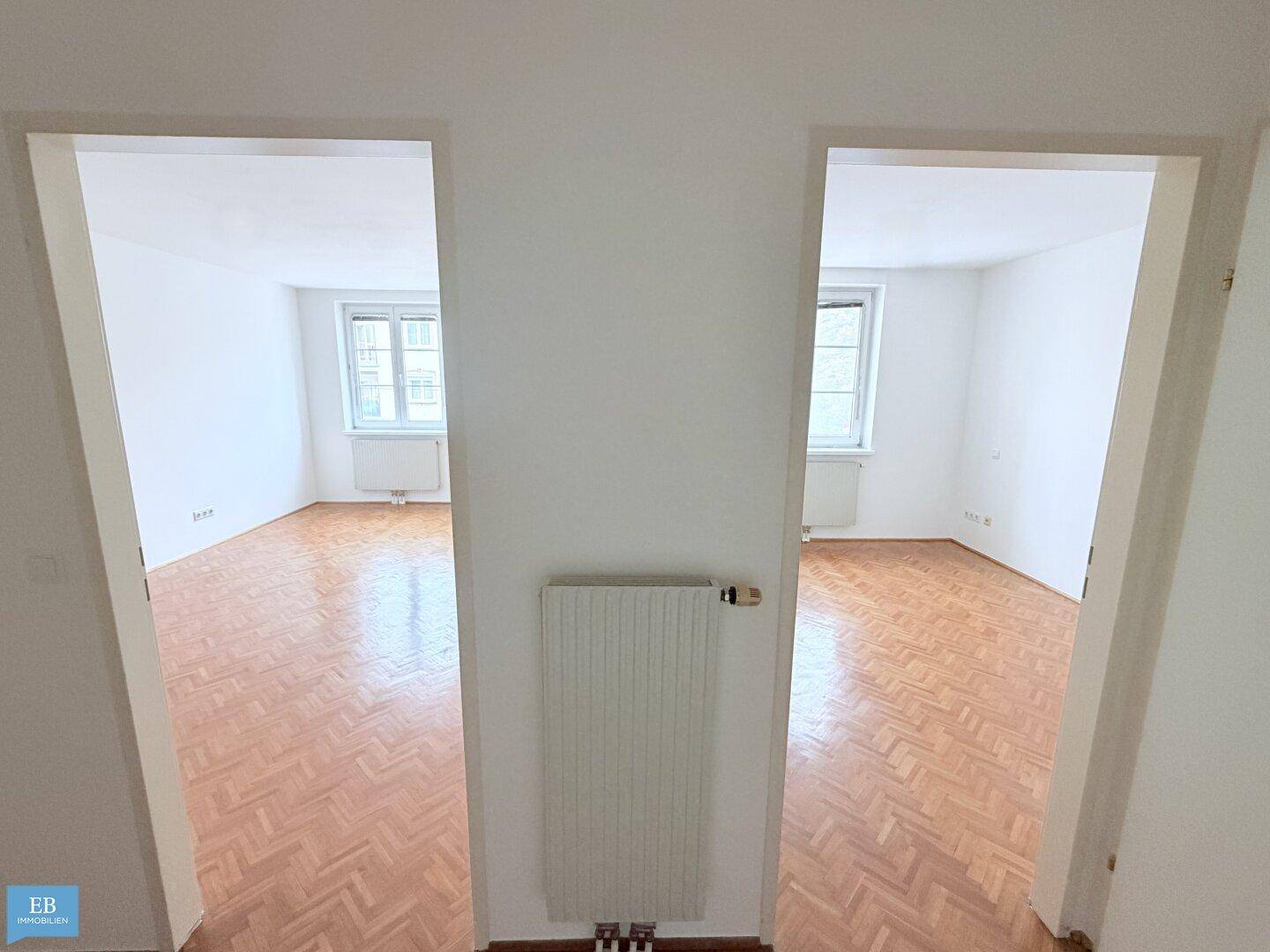 Flur mit Blick in zwei separate Zimmer, beide mit Fischgrätparkett.