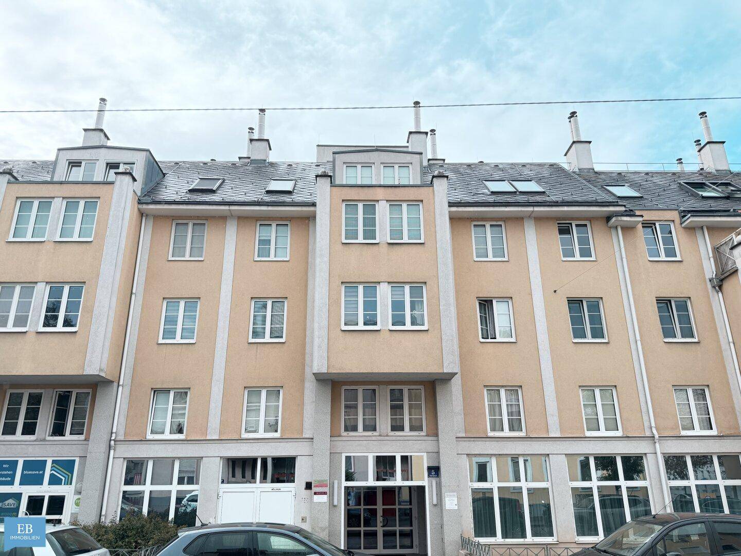 Mehrstöckiges Wohngebäude mit beiger Fassade und vielen Fenstern.