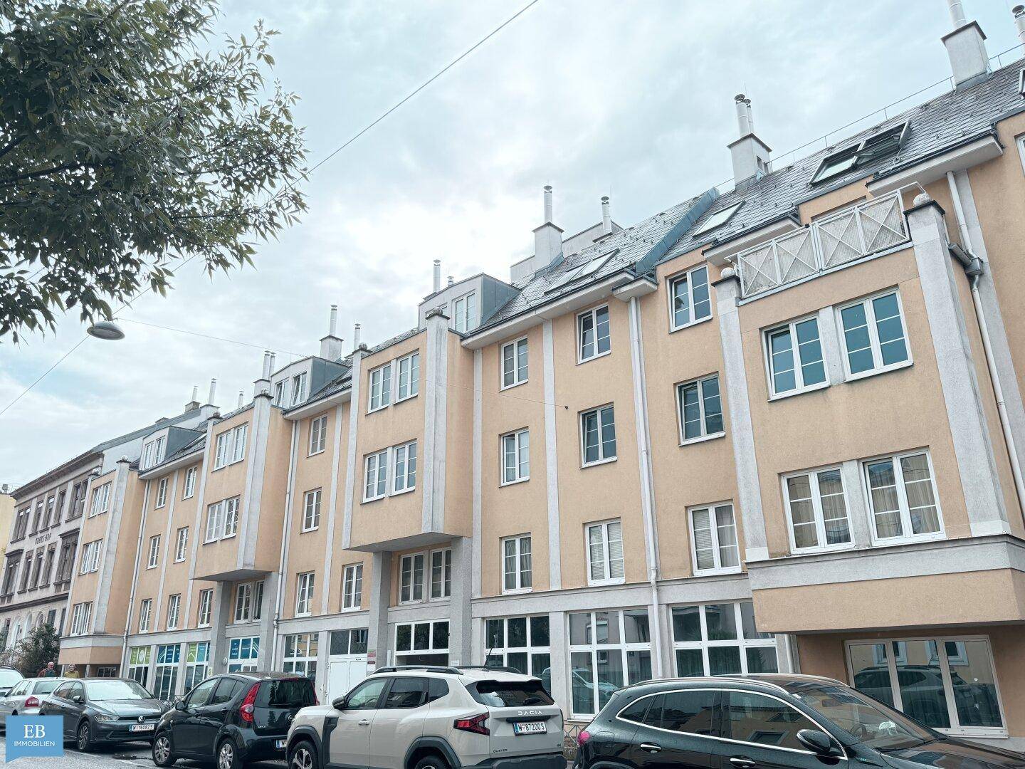 Ansicht eines modernen Wohngebäudes mit beiger Fassade und vielen Fenstern.