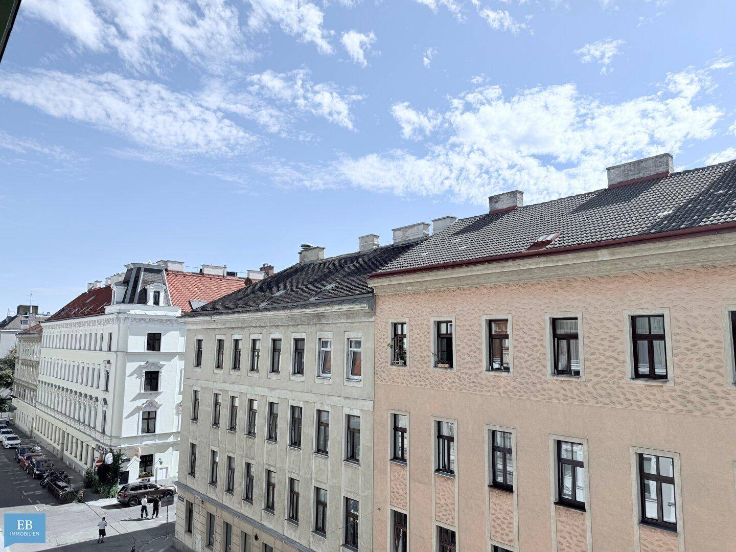 Blick auf eine belebte Stadtstraße mit historischen Gebäuden und klarem Himmel.