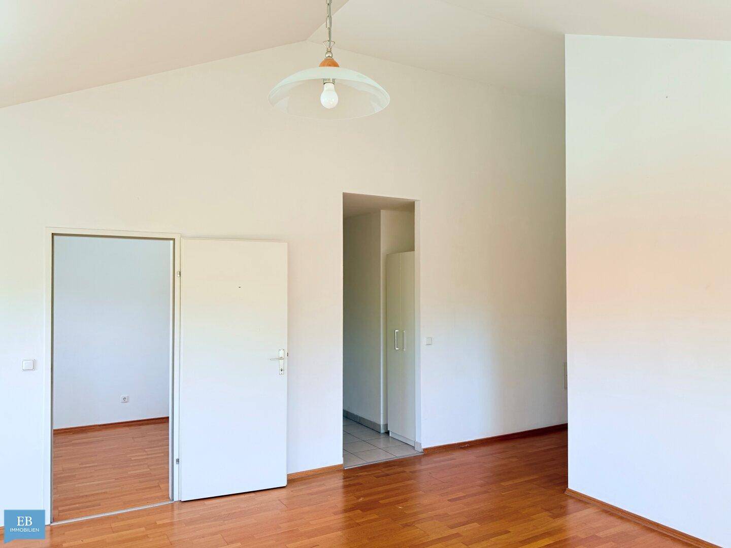 Geräumiges, helles Zimmer mit Holzparkettboden und Zugang zu weiteren Räumen.