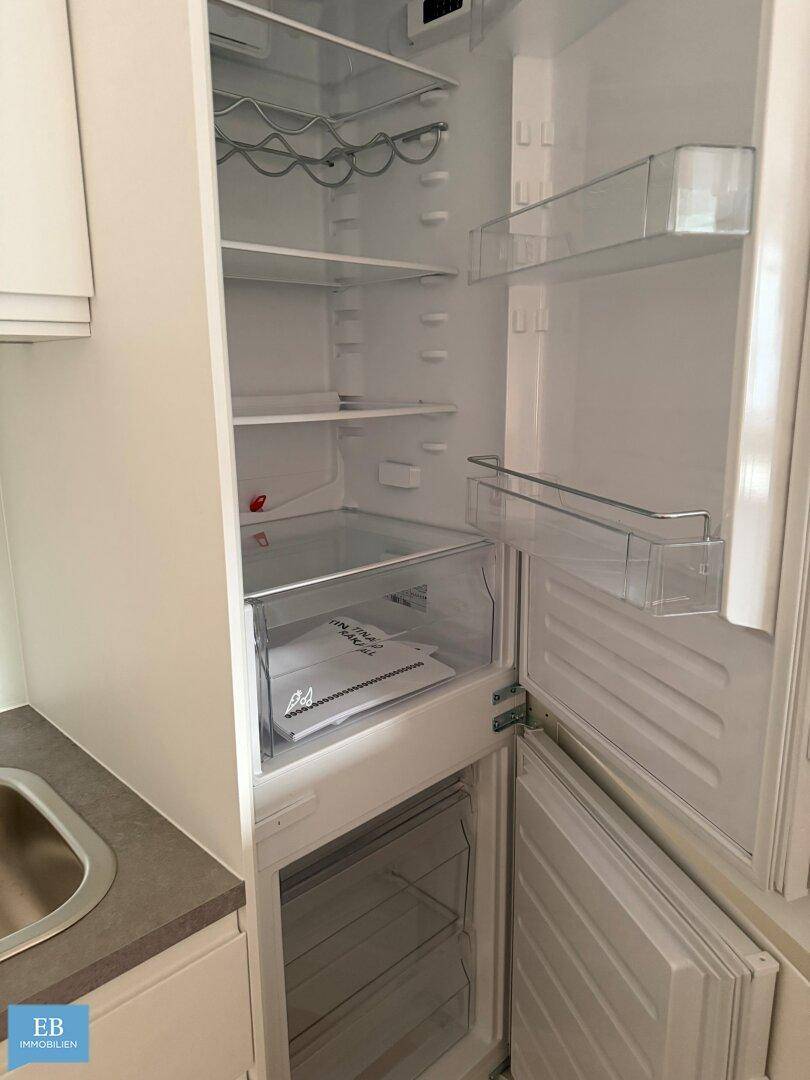 Offener Kühlschrank in einer modernen Einbauküche, bereit zur ersten Nutzung.