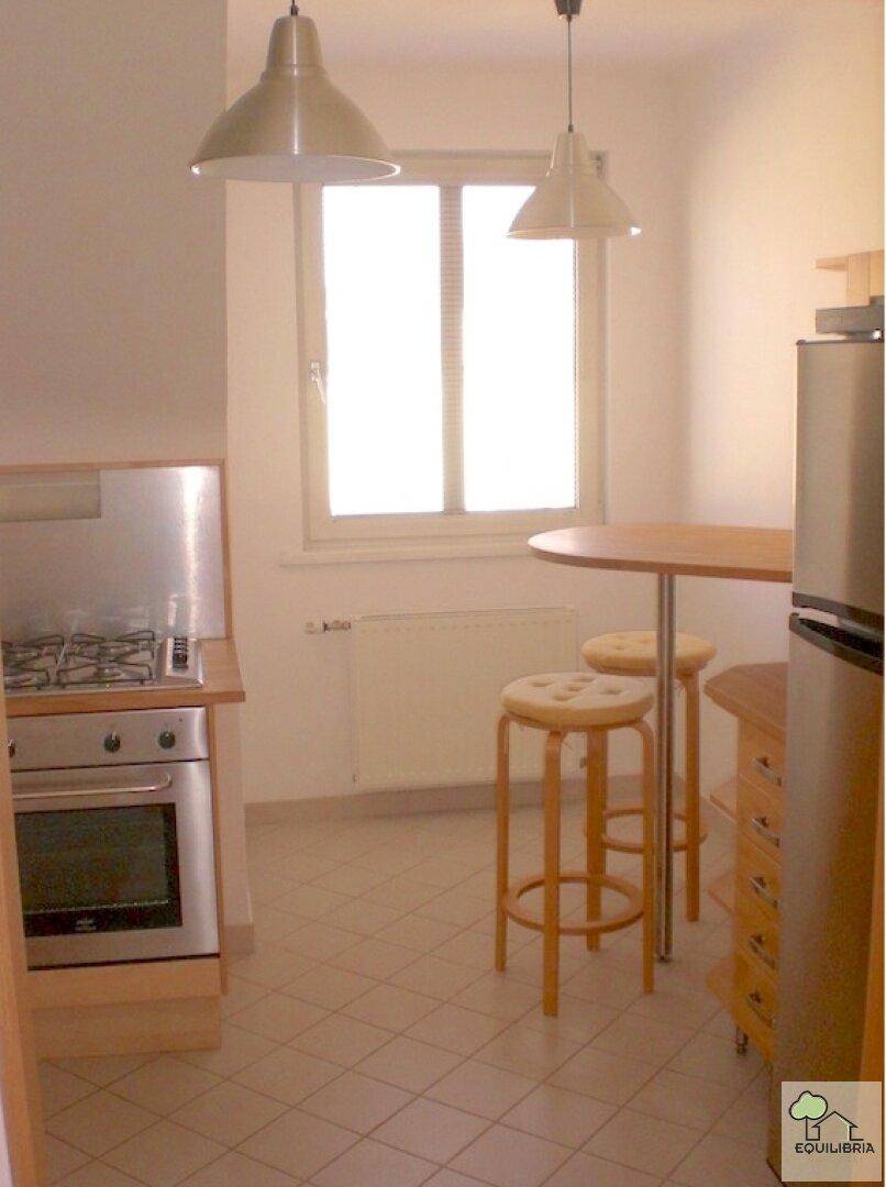 Funktionale Küche mit Gasherd, Backofen und Essbereich mit Barhockern am Fenster.