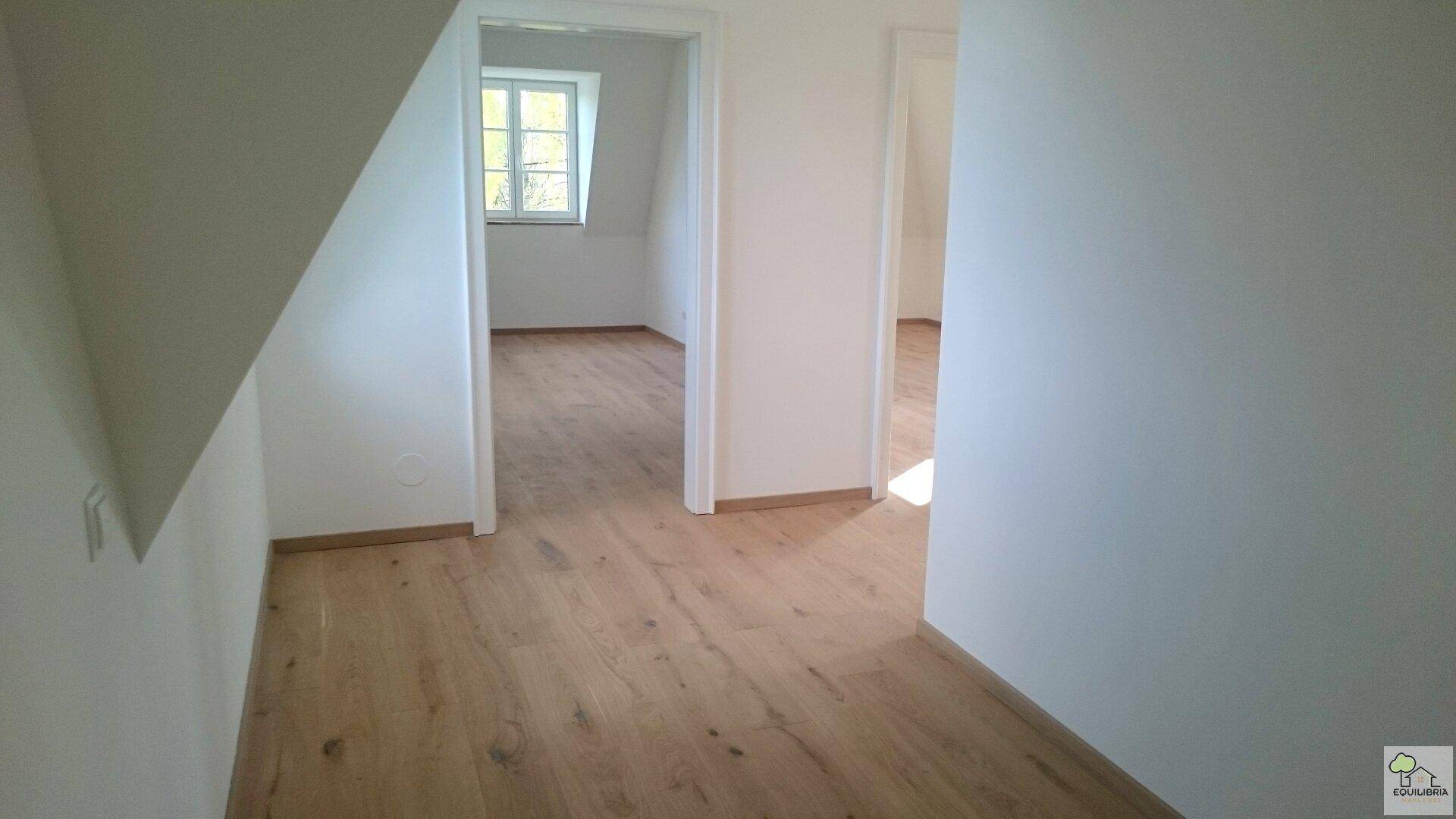 Heller Flur mit Holzfußboden, der zu mehreren Zimmern im Obergeschoss führt.