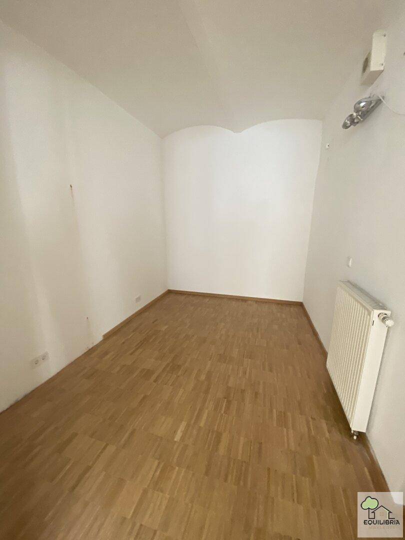 Kleiner, leerer Raum mit Holzboden und weiß gestrichenen Wänden, bereit zur Nutzung.