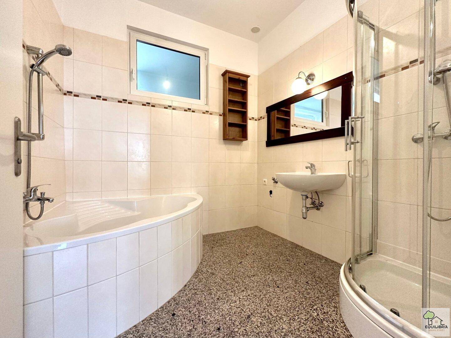Helles Badezimmer mit Eckbadewanne, Duschkabine, Einzelwaschbecken und Fenster.
