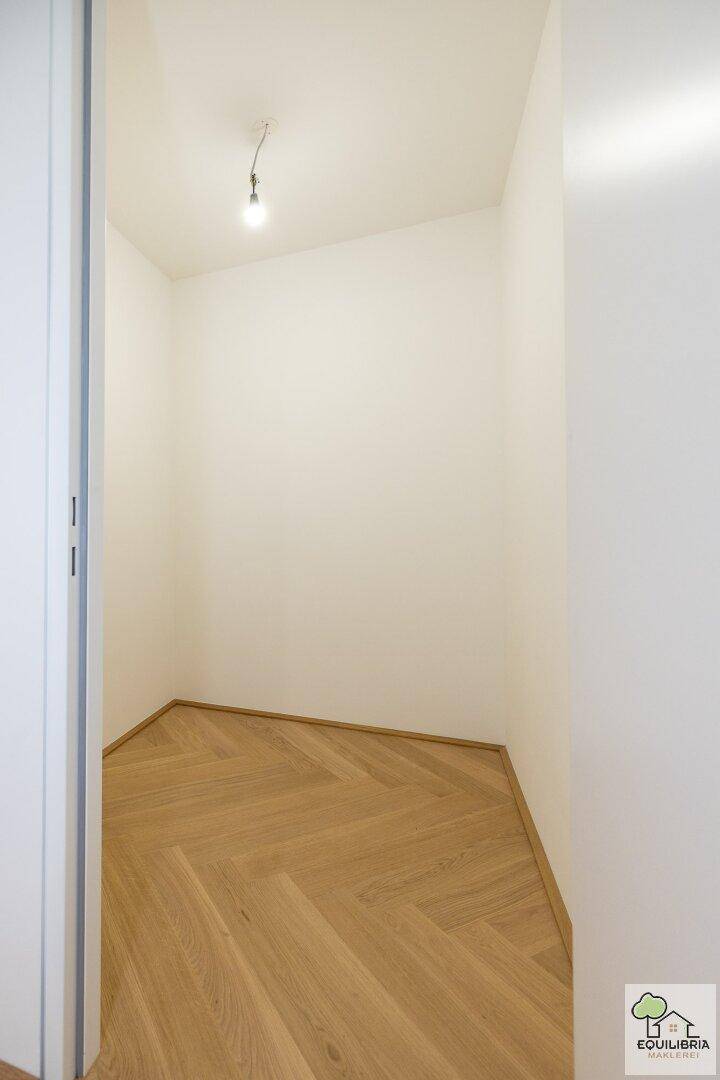 Kleiner, heller Abstellraum mit Fischgrätparkett und weißen Wänden, ideal für zusätzlichen Stauraum.