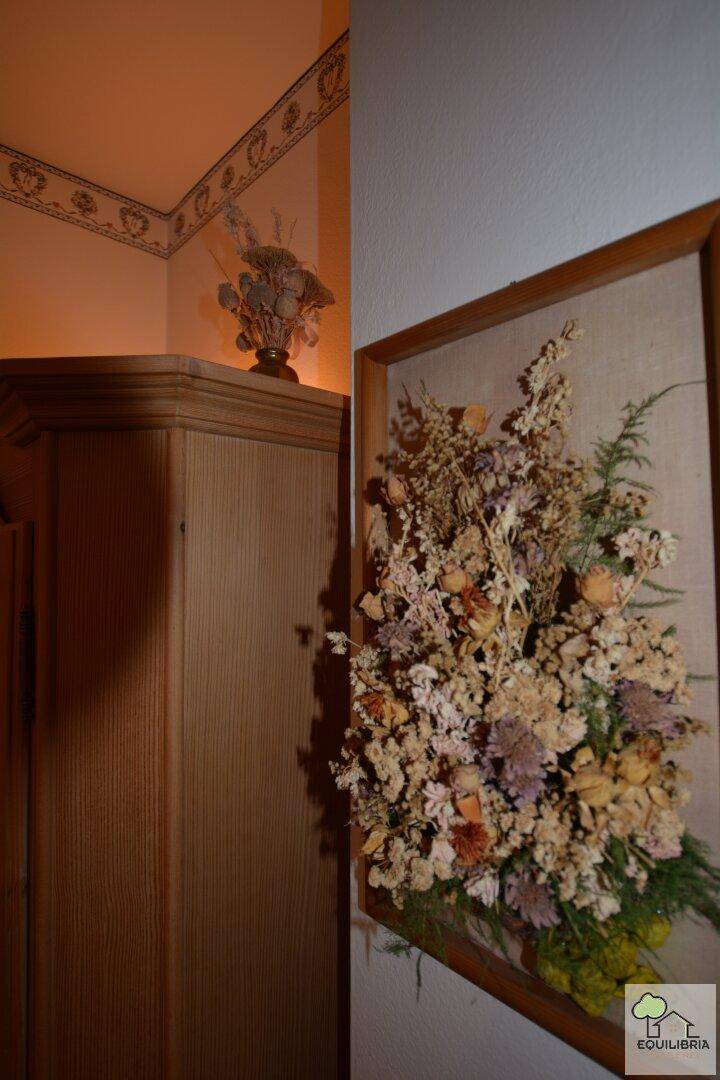 Detailansicht eines traditionellen Holzschranks mit getrockneten Blumen als rustikale Dekoration.