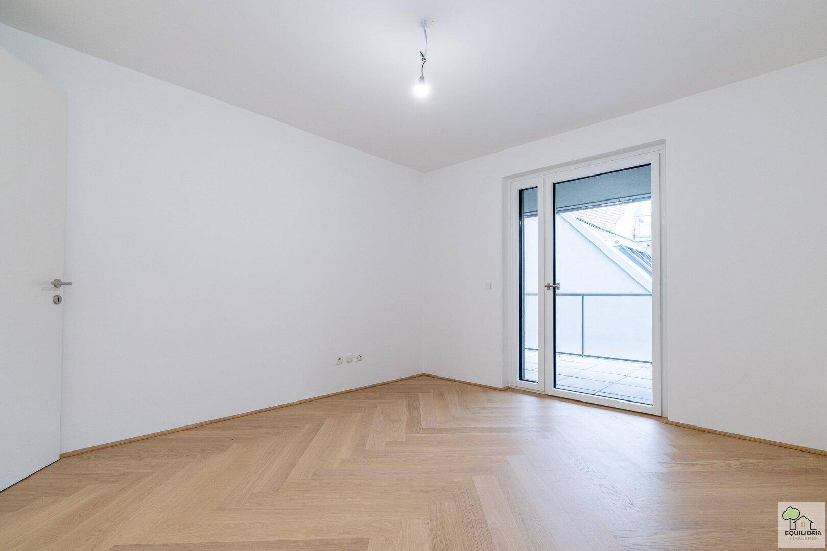 Weiteres helles Schlafzimmer mit Fischgrätparkett und Balkonzugang, ideal für Ruhe.