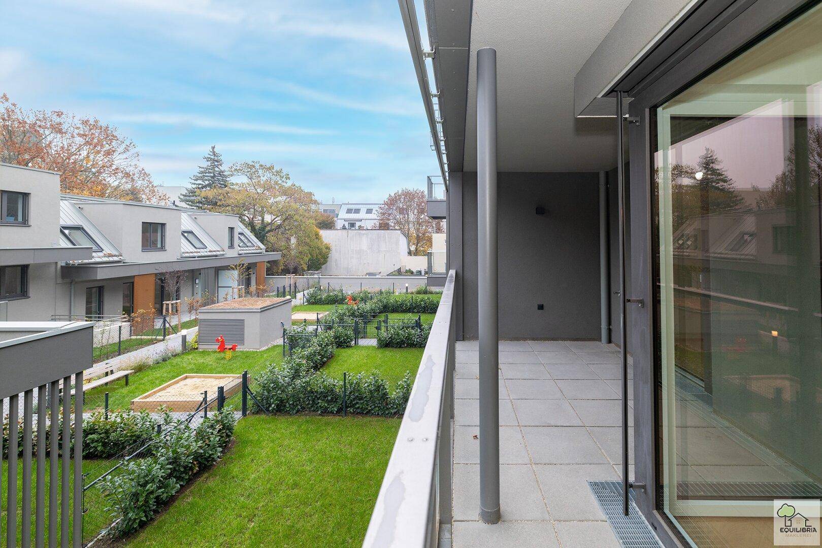 Balkon mit schöner Aussicht auf die grüne Anlage und den Kinderspielbereich im Hof.
