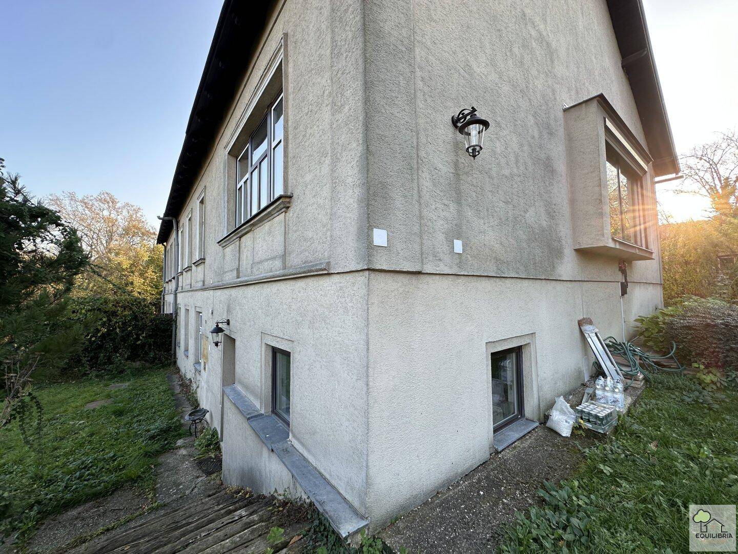Seitenansicht des Gebäudes mit verputzter Fassade und Fenstern im Erd- und Untergeschoss.