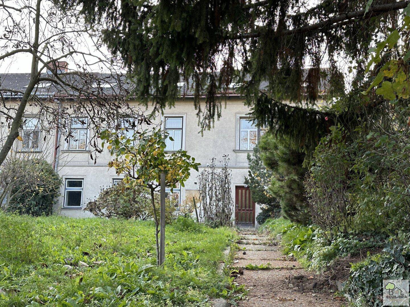 Vorderansicht des Hauses mit einem naturbelassenen Vorgarten und einem Zugangspfad.